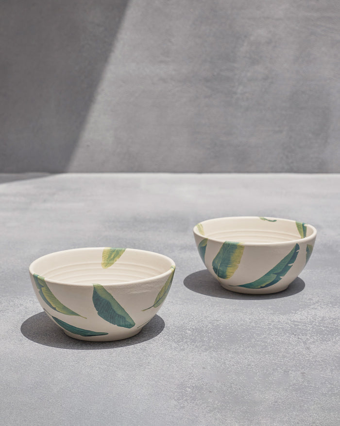 Pair of Ceylon cereal bowls with green banana-leaf motifs on cream stoneware.
