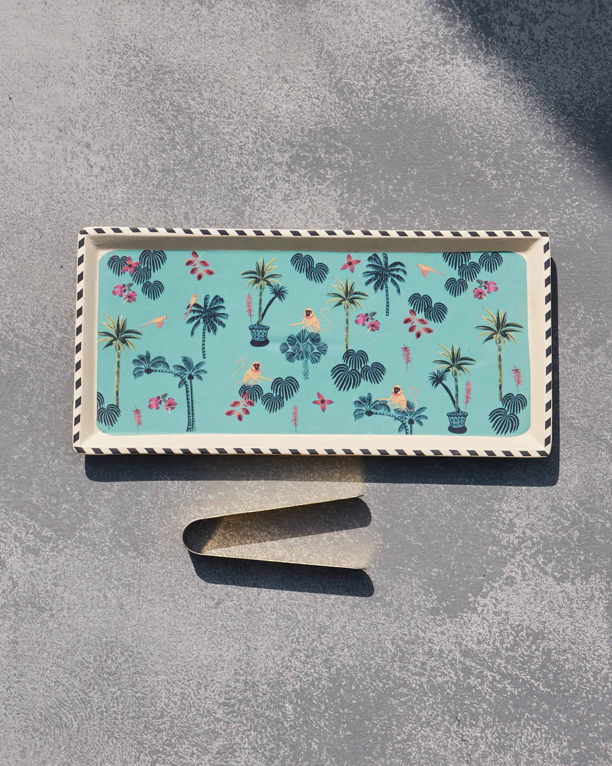 Tropico cookie tray with brass tongs laid out beneath it.