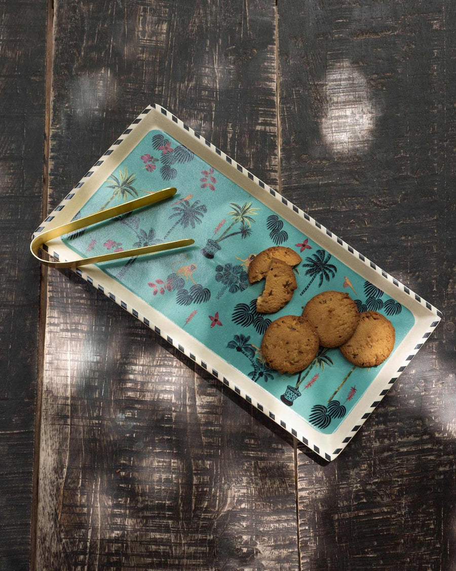 The teal Tropico tray with cookies and tongs on dark wood