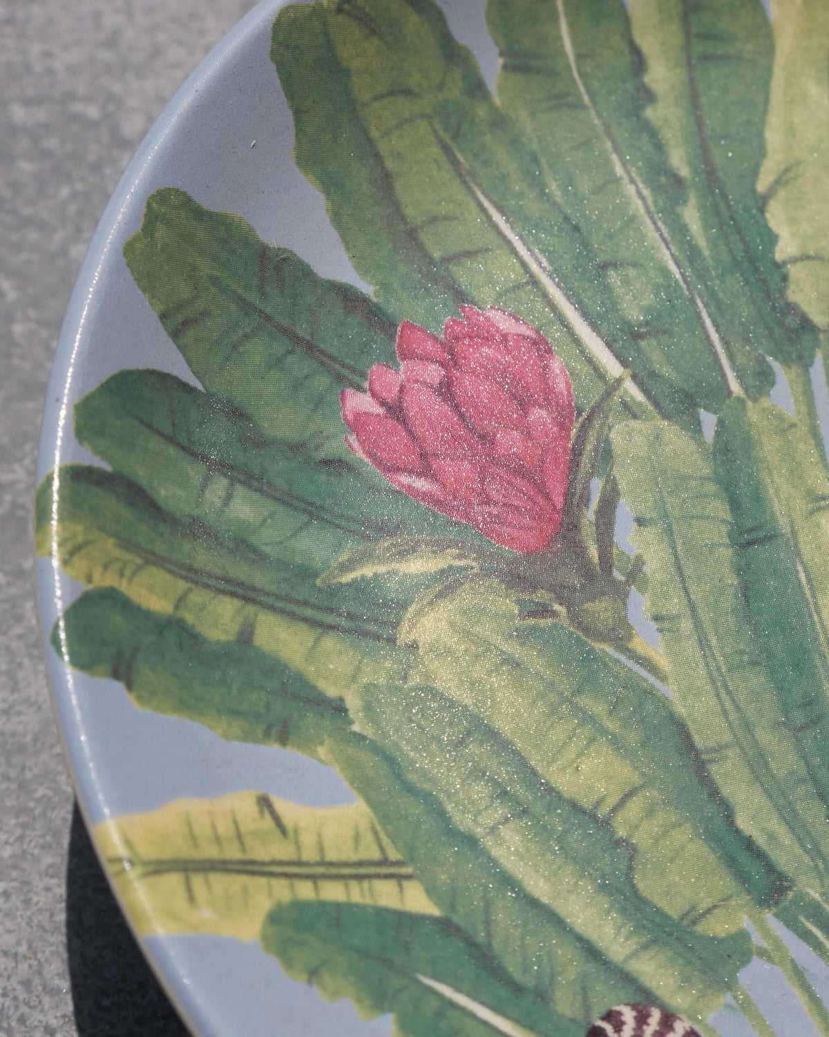 Close-up of Madagascar quarter plate showing banana leaves and a pink blossom.
