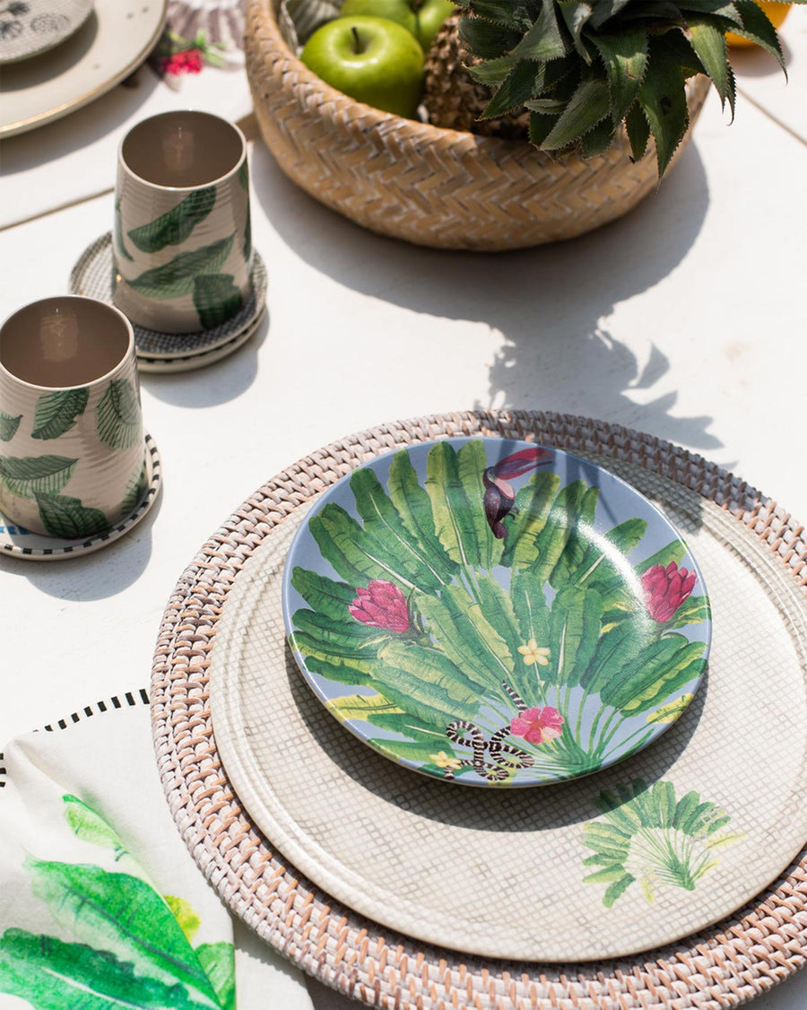 The Madagascar plate with a toucan print on a rattan charger outdoors