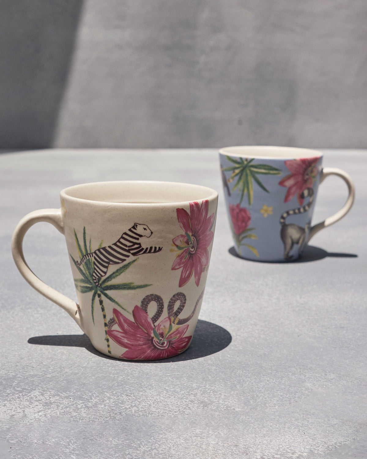 Wilderness Lemur mugs in cream and blue with tropical flowers and animal motifs.