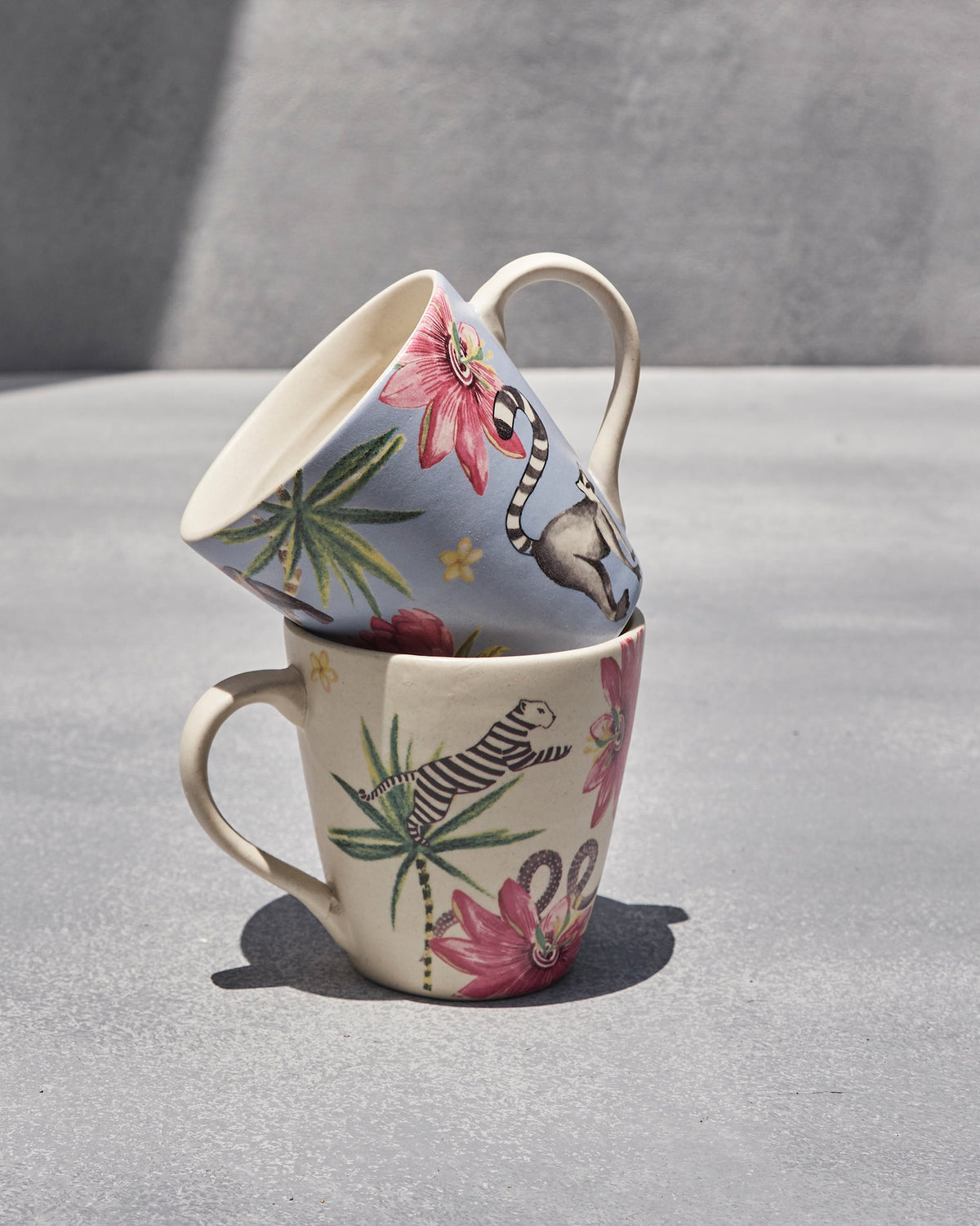 Stacked Wilderness Lemur mugs in cream and blue with tropical animal motifs.