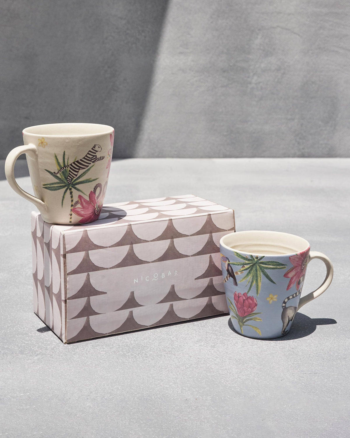 Cream tiger mug and blue lemur mug shown with a scalloped Nicobar gift box.