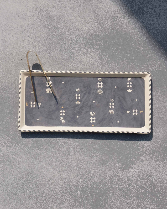 Nizara cookie tray with brass tongs and white animal and star motifs.