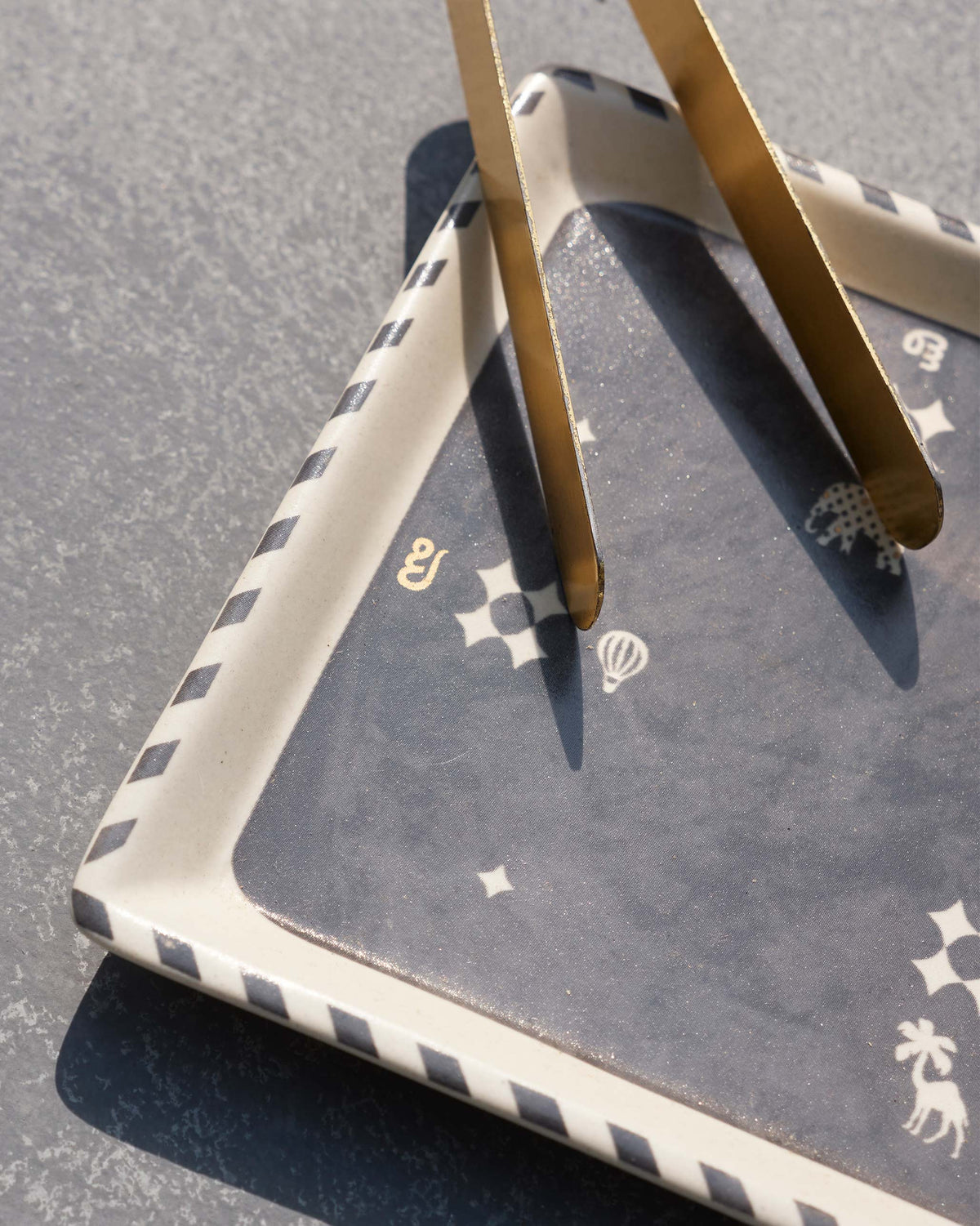 Close-up of Nizara cookie tray with brass tongs and giraffe and balloon motifs.