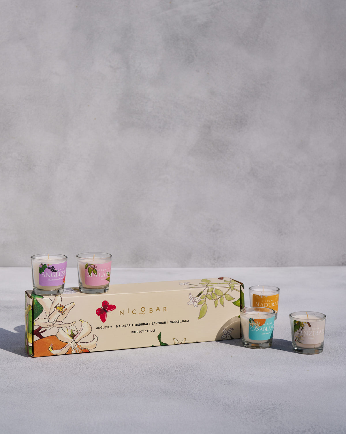 Nicobar Jar Candles Set of 5 arranged around its cream gift box.