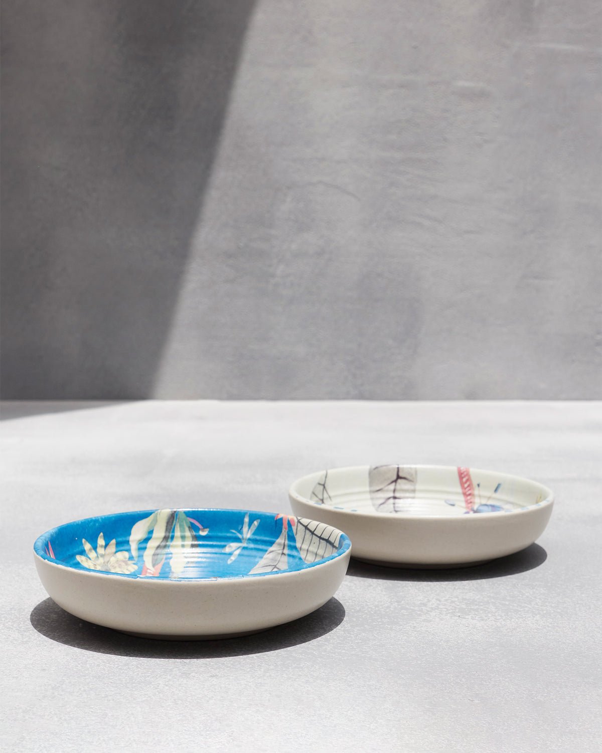 Pair of Mahi shallow bowls with blue and cream botanical interiors.