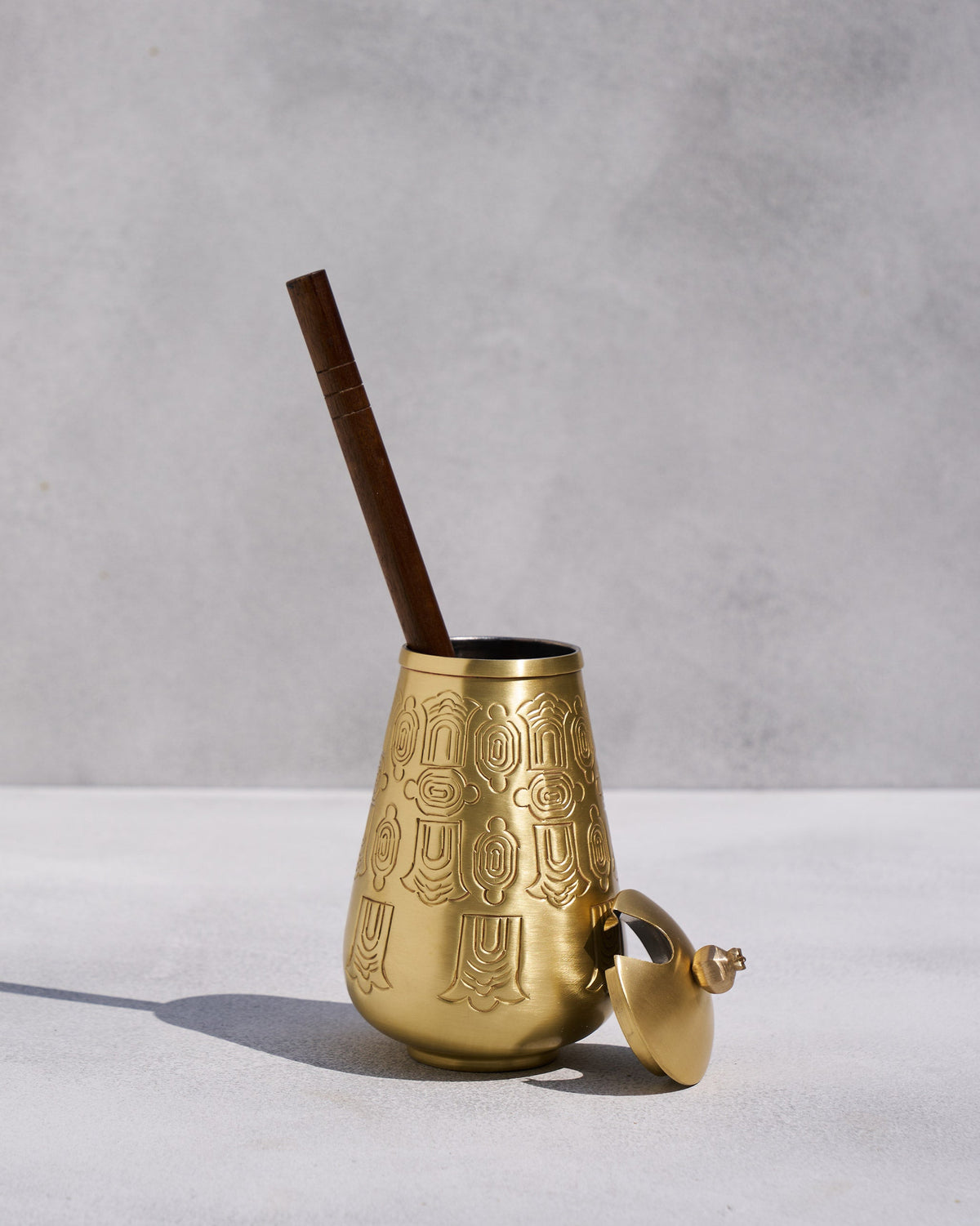 Heritage Churn Set brass vessel with its lid aside and a wooden stirrer inside.