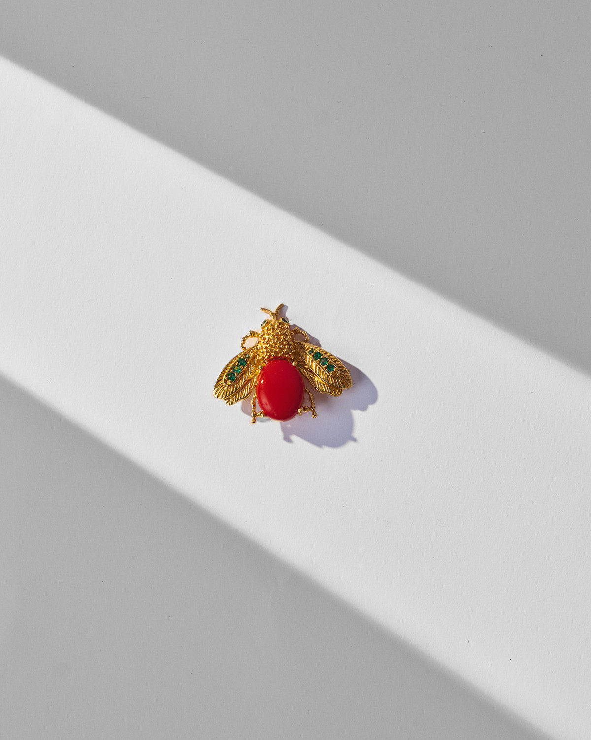 Gold Bug brooch with a red stone body and green wing accents.