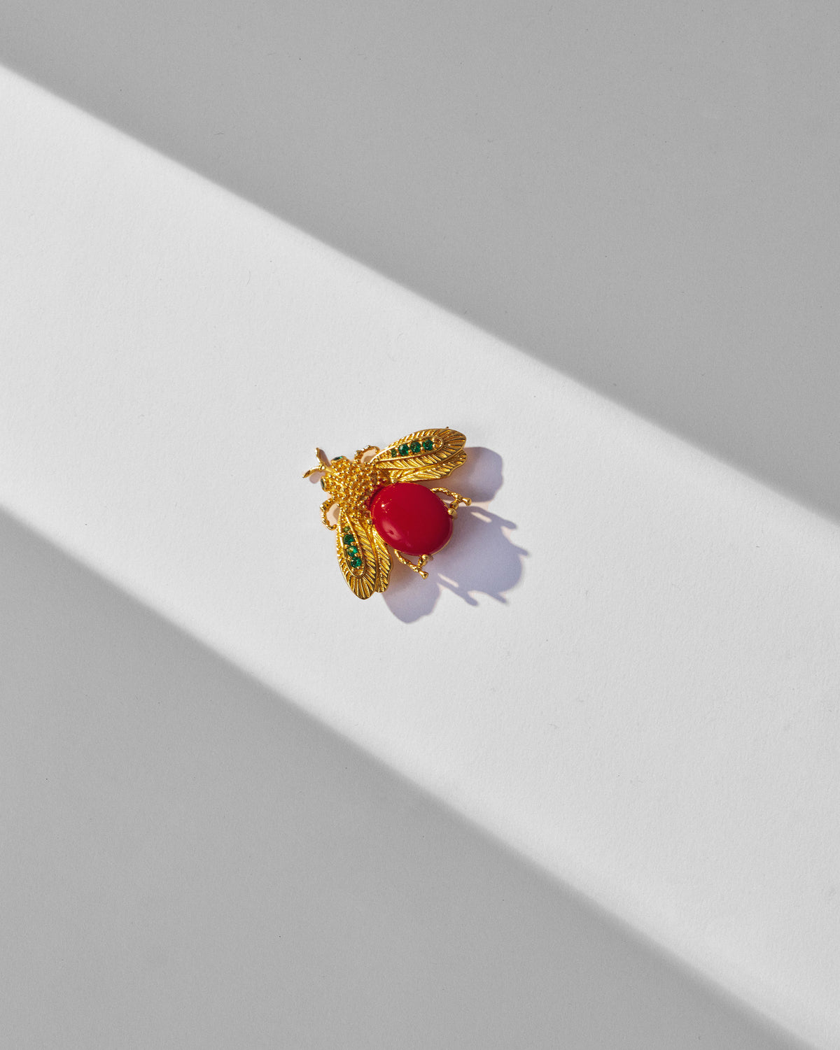 Close-up of the gold Bug brooch with a red body and green wing stones.