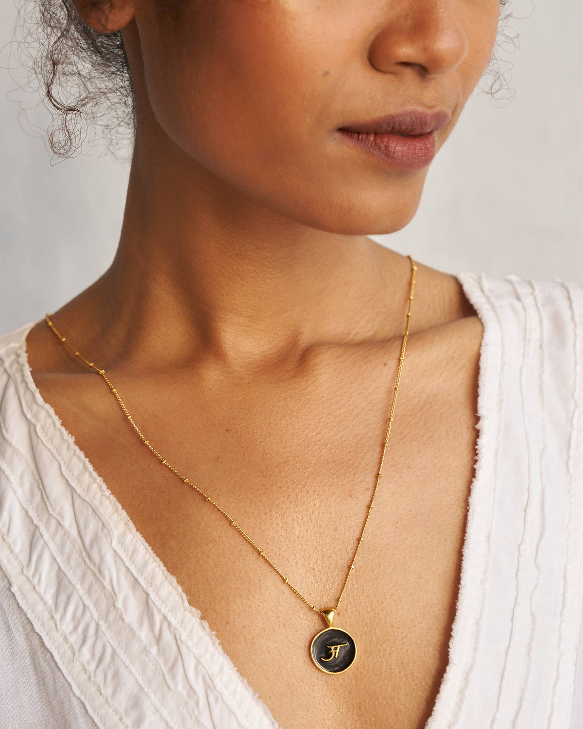 Black and gold Alphabet A charm worn on a fine gold chain.