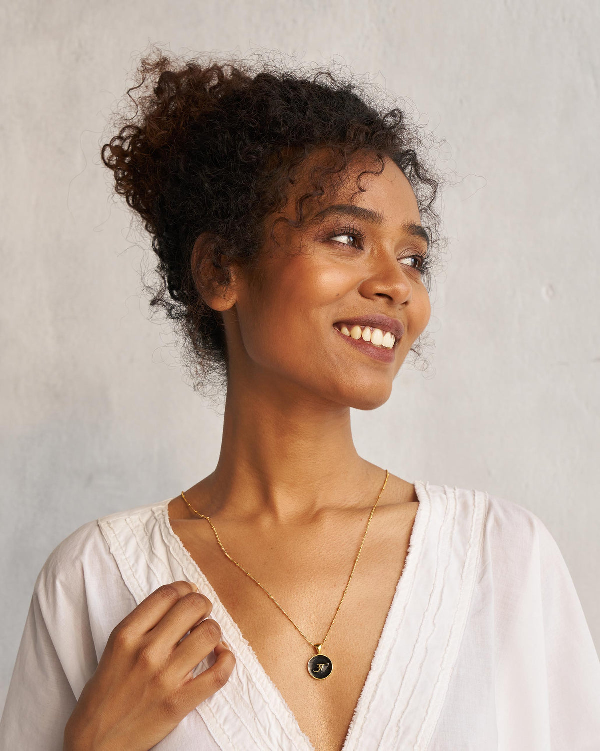 Person wearing a black and gold alphabet charm necklace.