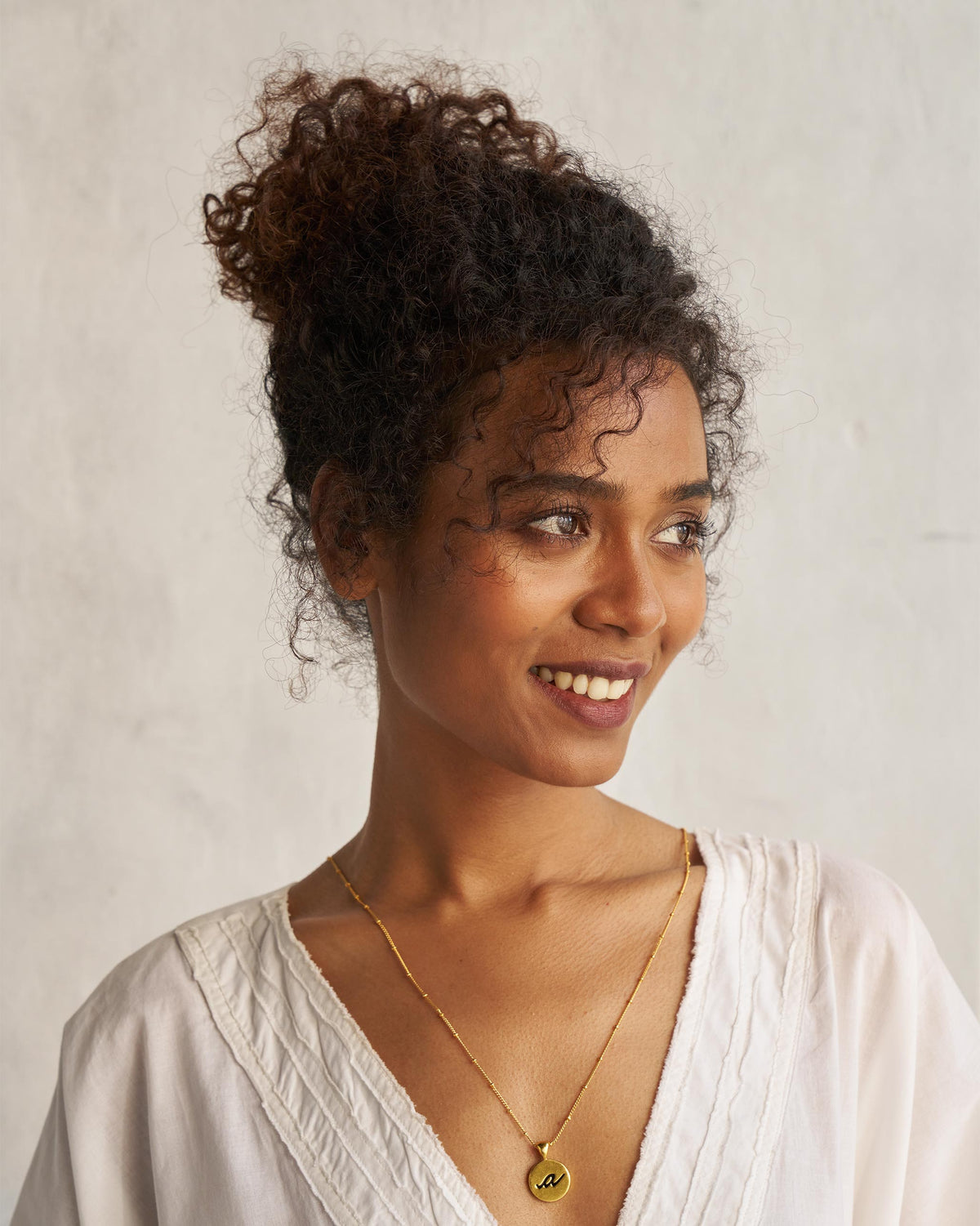 Person wearing a gold alphabet charm on a fine chain.