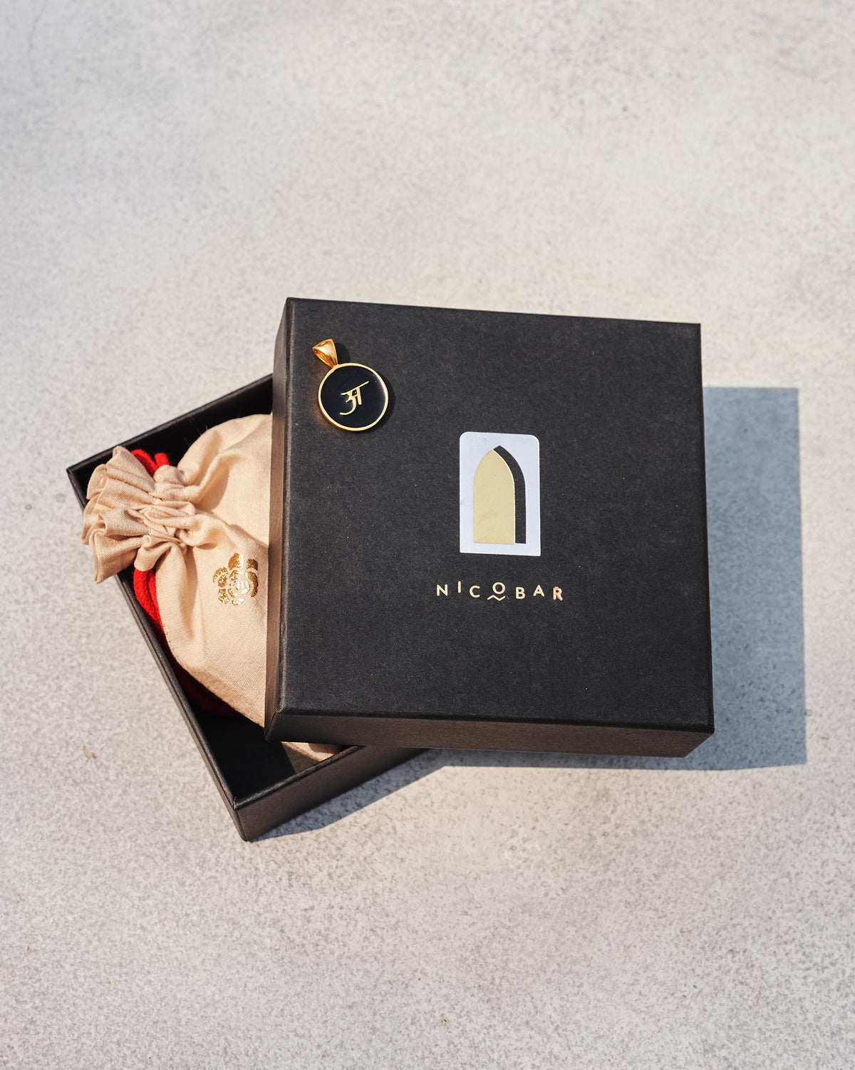 Black and gold Alphabet A charm on a Nicobar gift box.