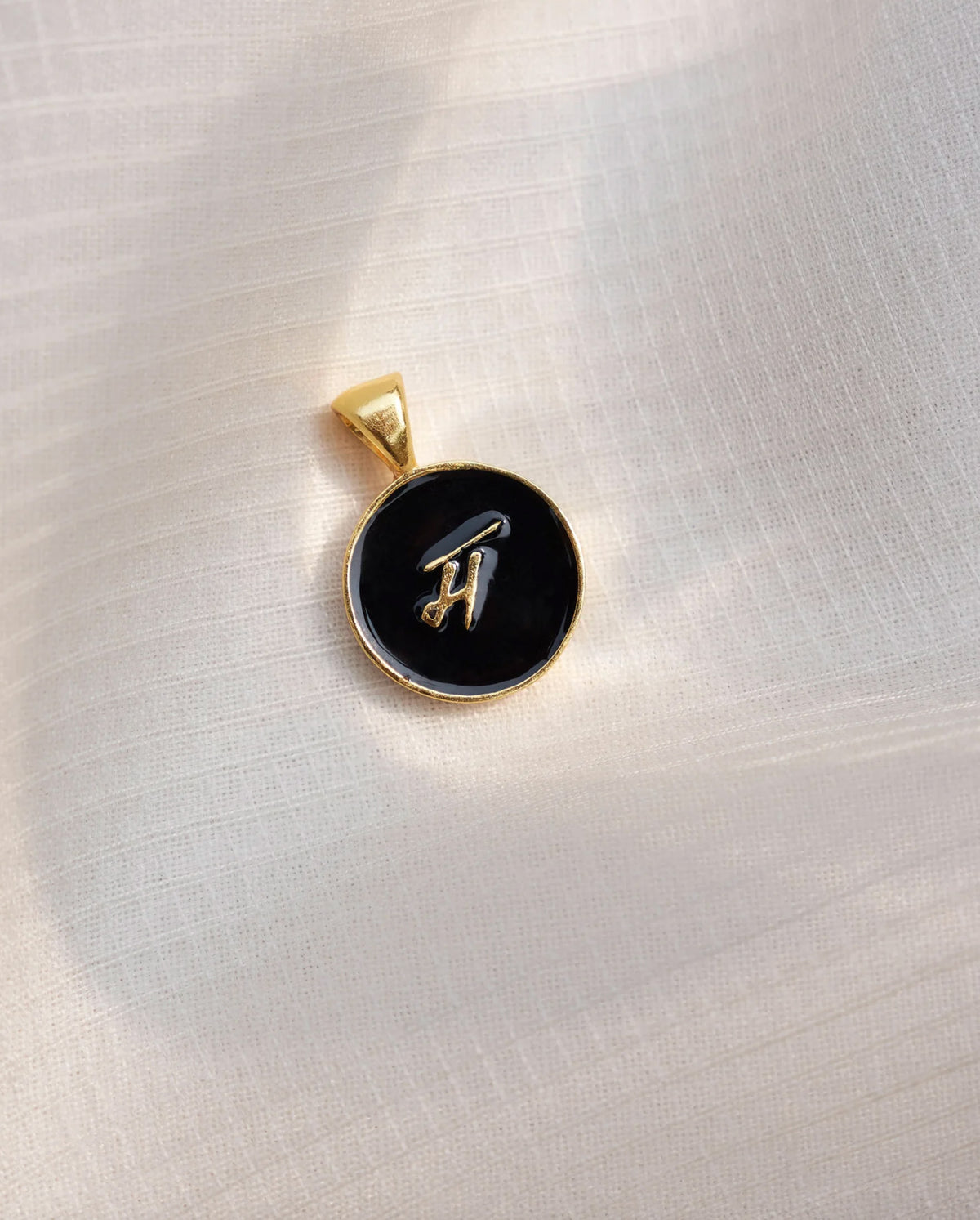 Alphabet M charm with a gold letter on a black enamel face.