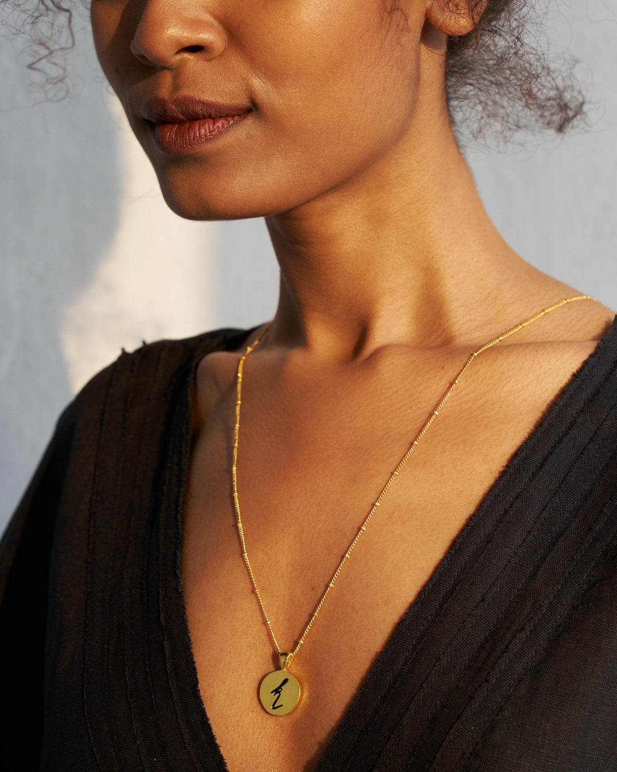 Gold Alphabet K charm with a black script letter k when worn.