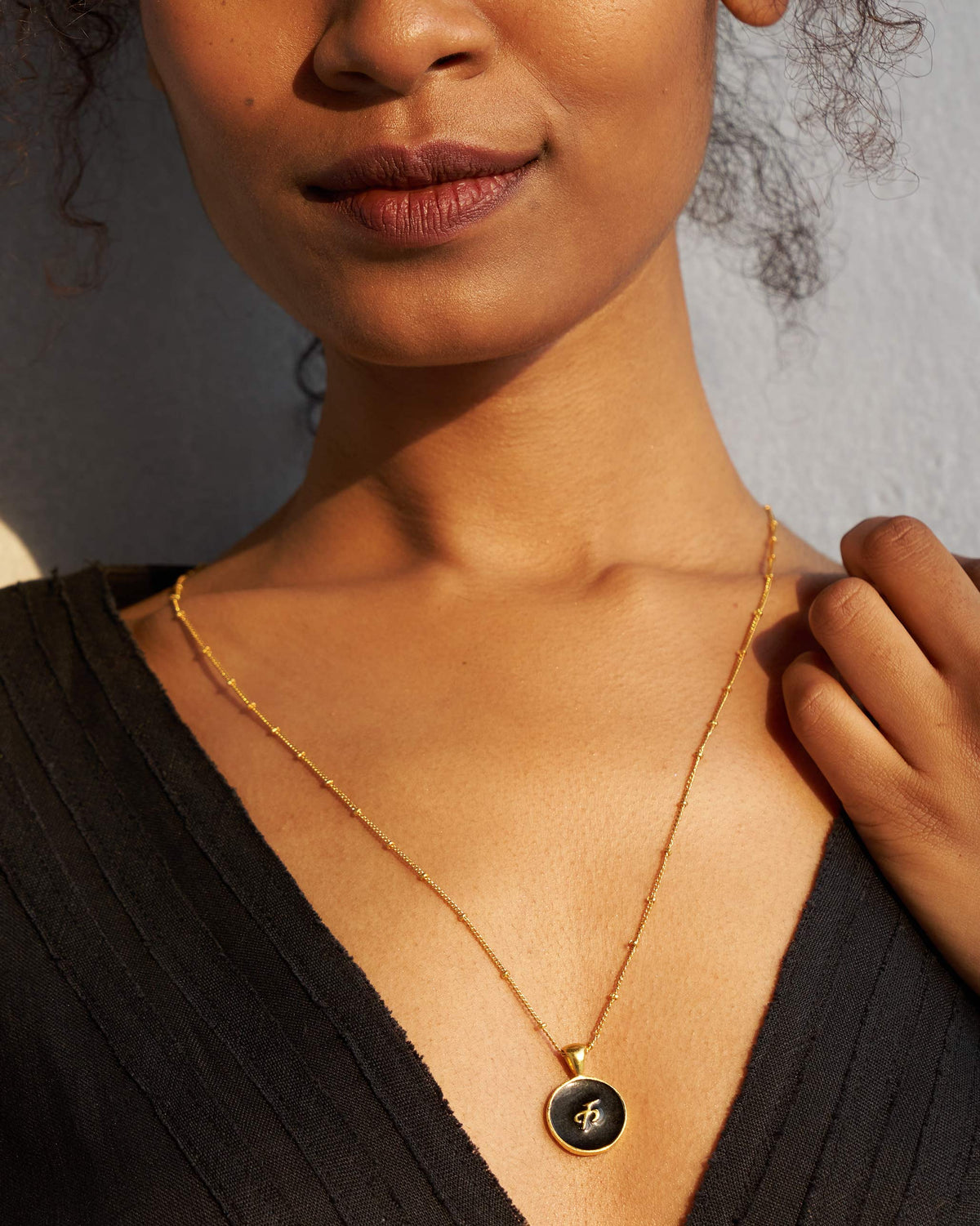Black and gold Alphabet K charm with a Devanagari letter worn on a satellite chain.