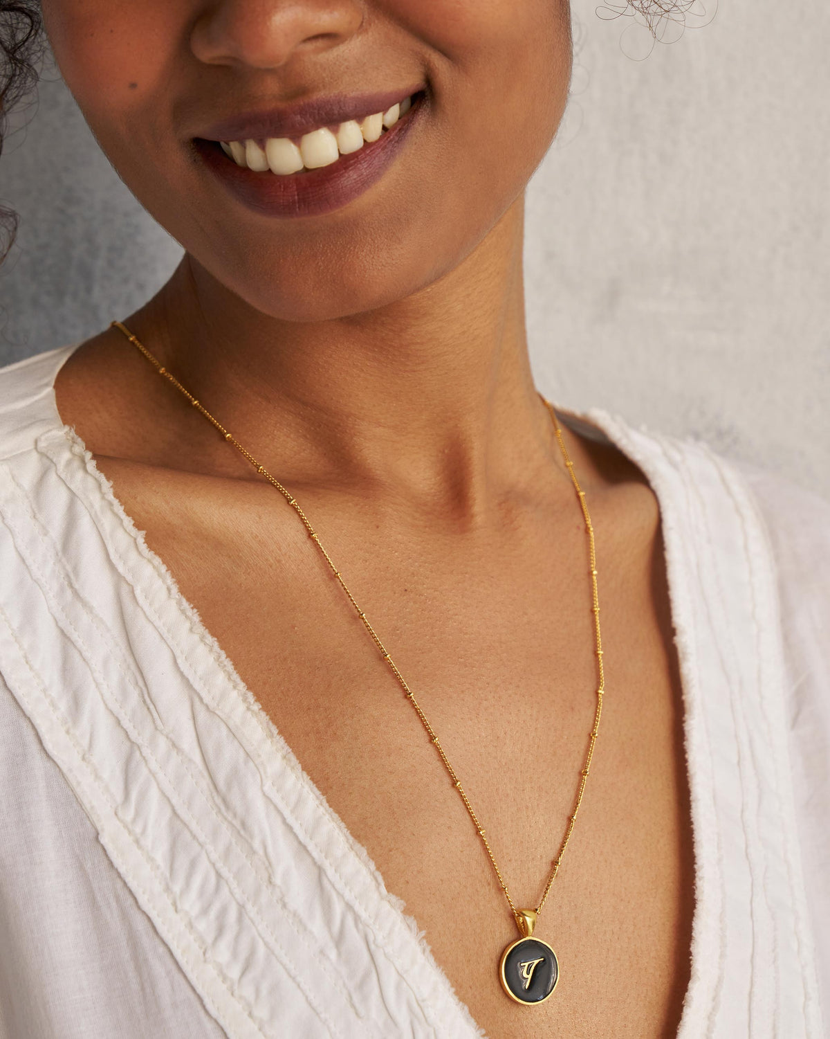 Black and gold Alphabet P charm with प worn on a satellite chain.