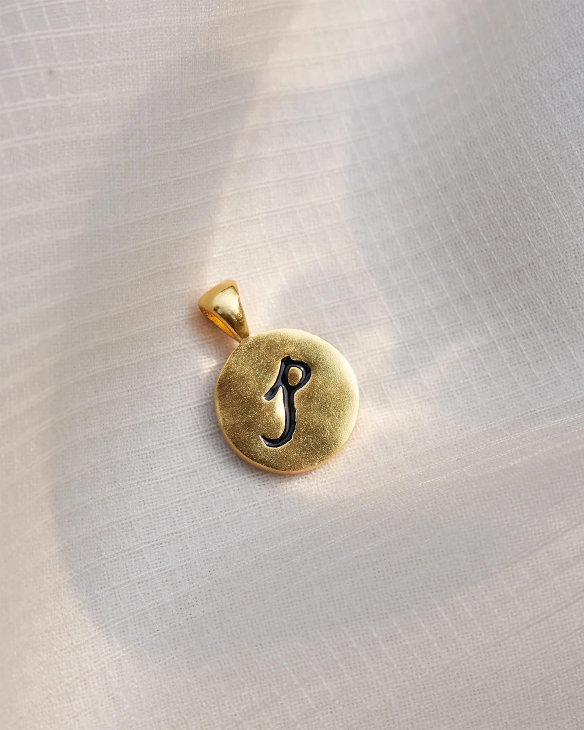 Close-up of a gold Alphabet P charm with a black script p.
