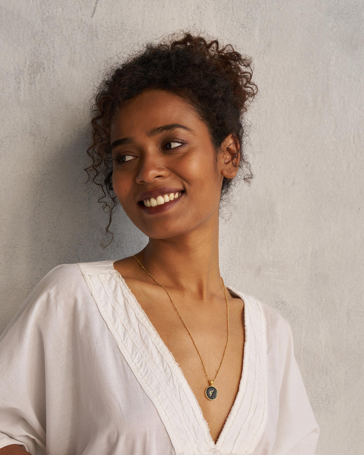 Person wearing a black and gold Alphabet P charm necklace.