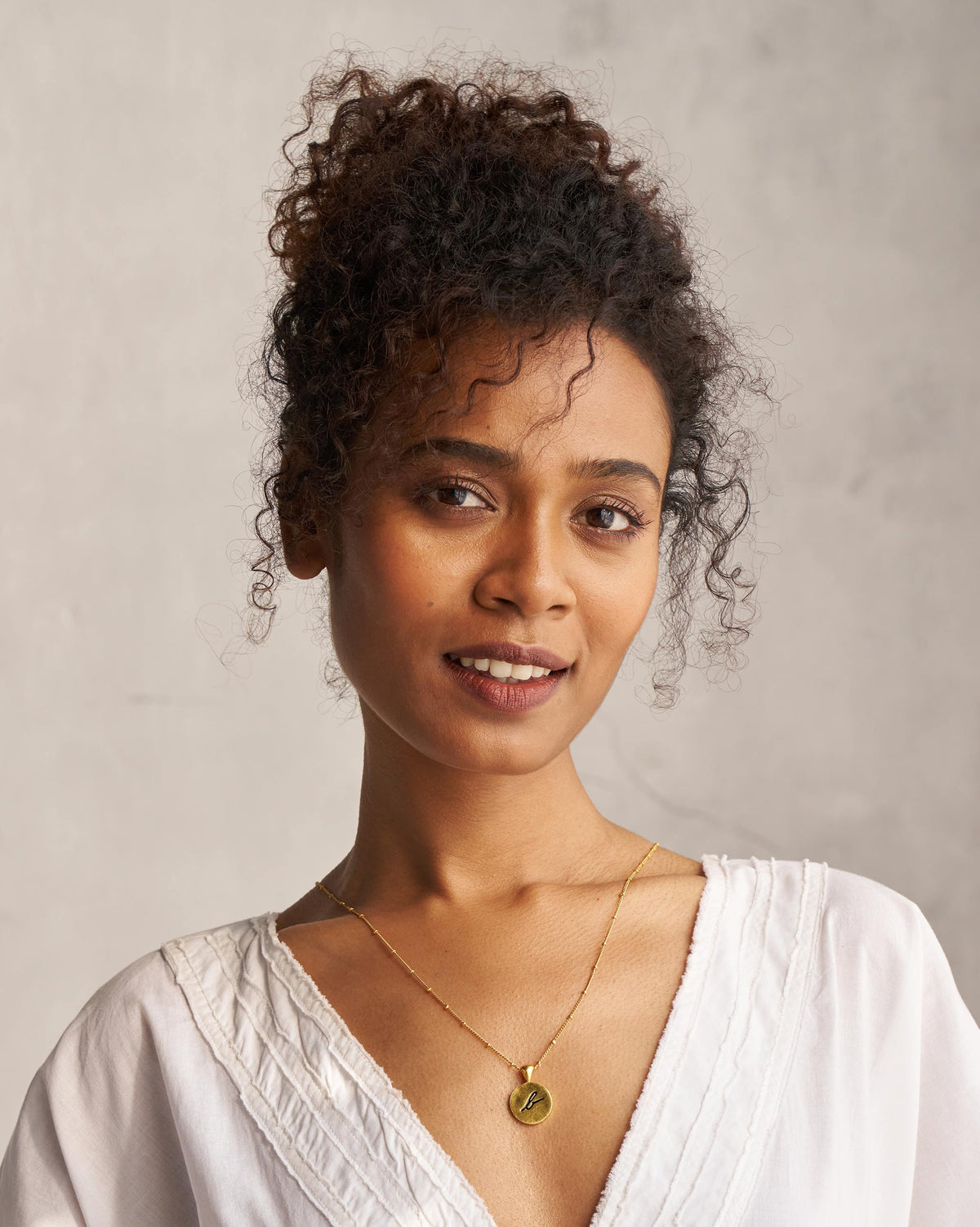 Alphabet B charm necklace worn with a white V-neck top.