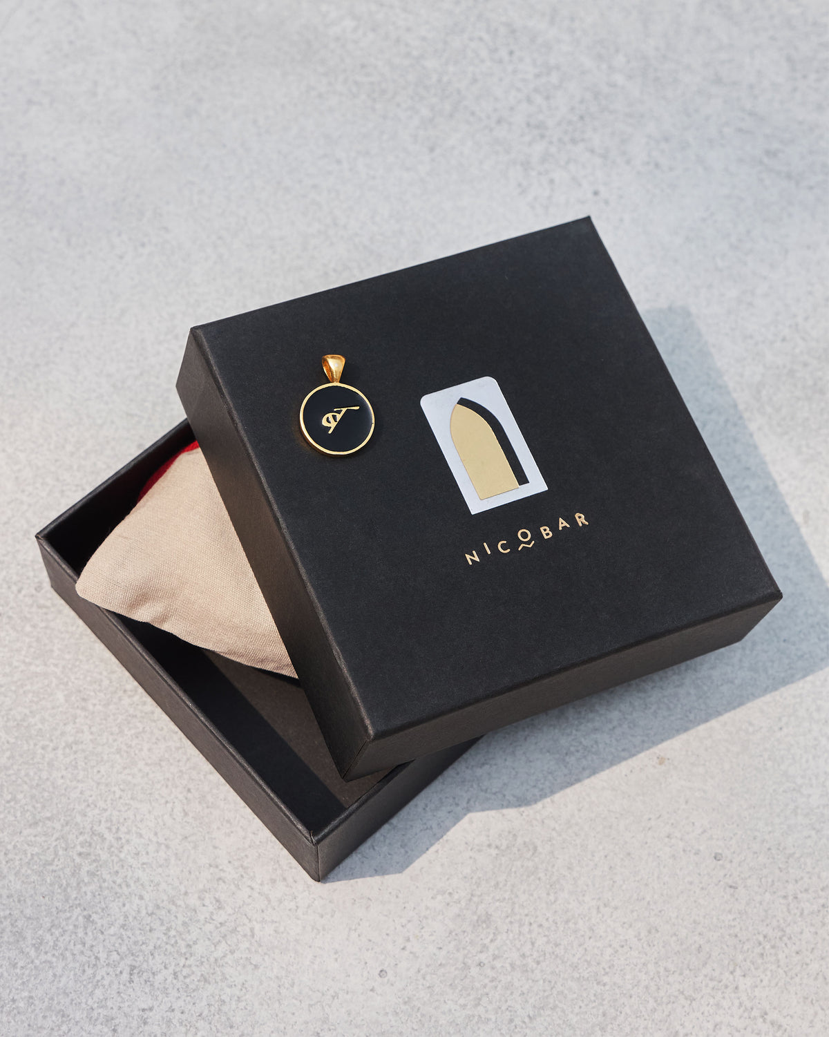 Black and gold alphabet charm on a Nicobar gift box.