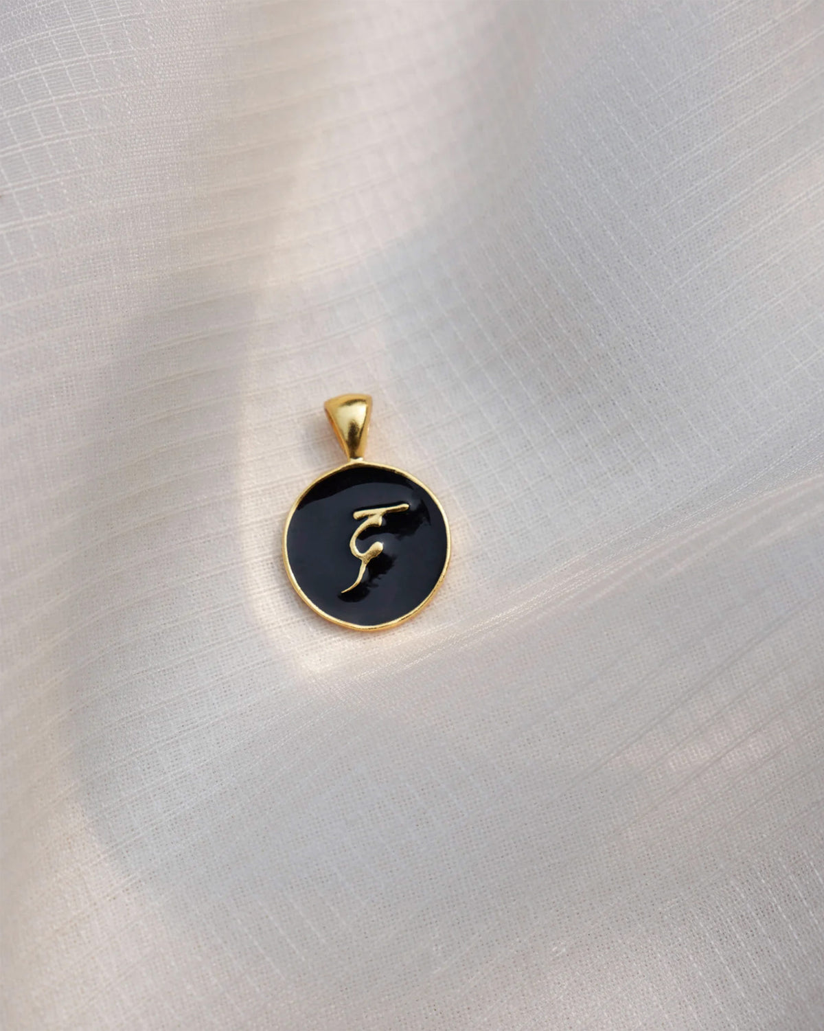Close-up of a black and gold Alphabet D charm with a gold letter.