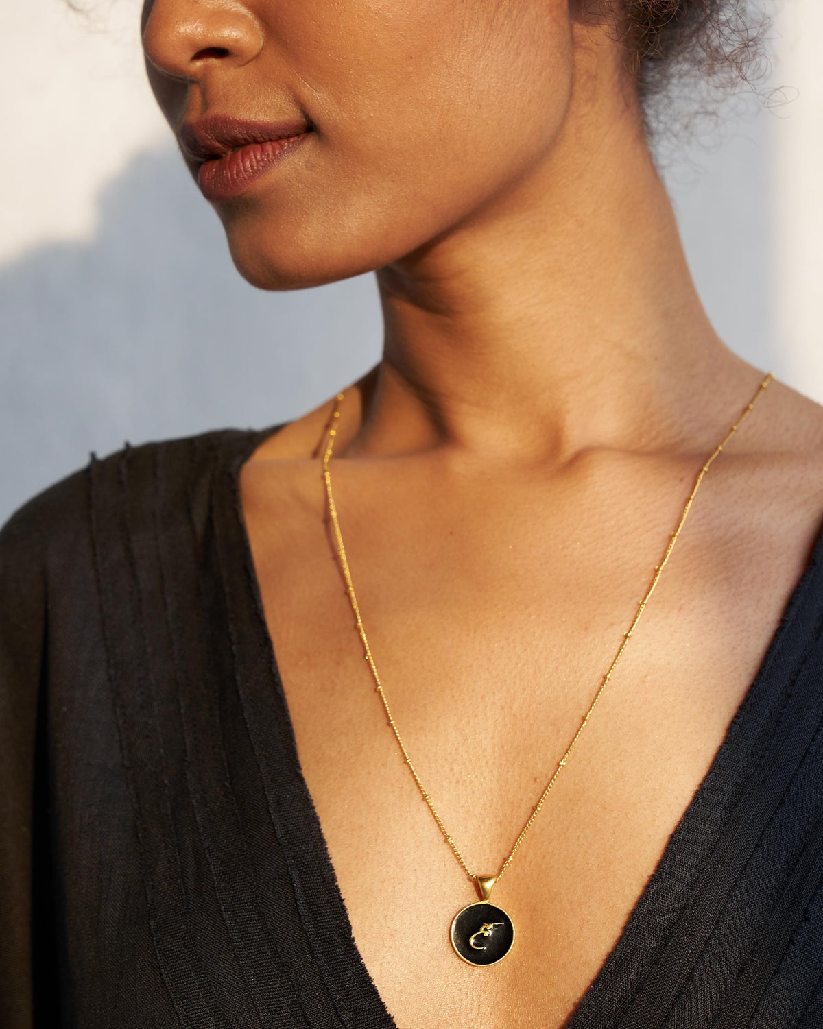 Black and gold Alphabet H charm with a Devanagari letter worn on a satellite chain.