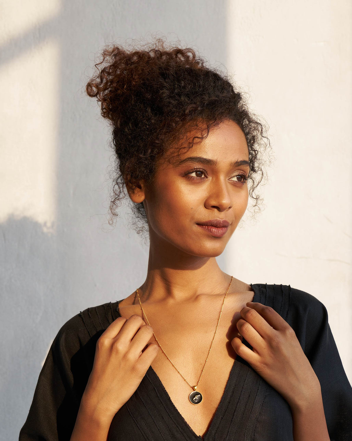 Person wearing a black and gold Alphabet H charm necklace.