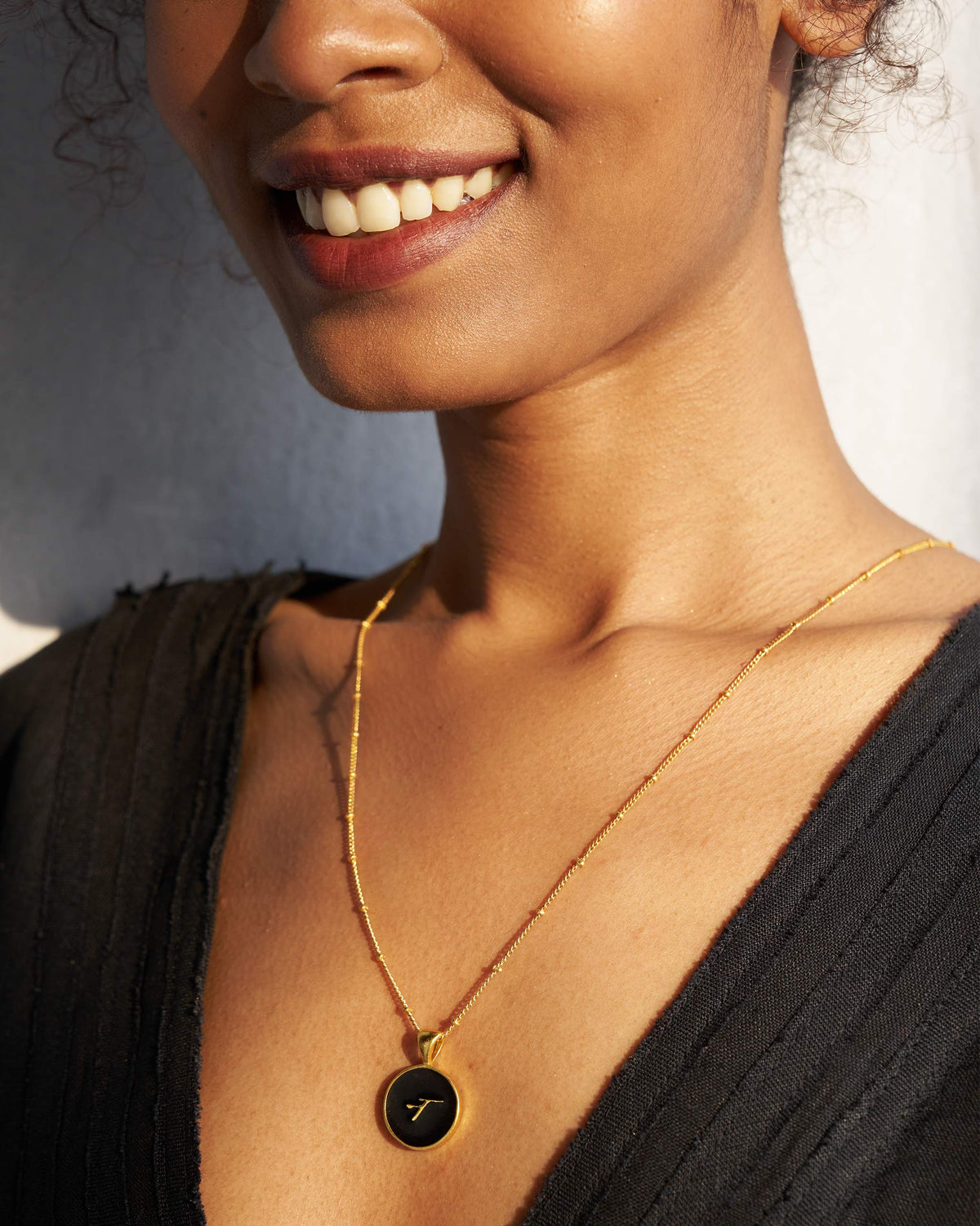 Black and gold Alphabet N charm with a Devanagari letter worn on a satellite chain.