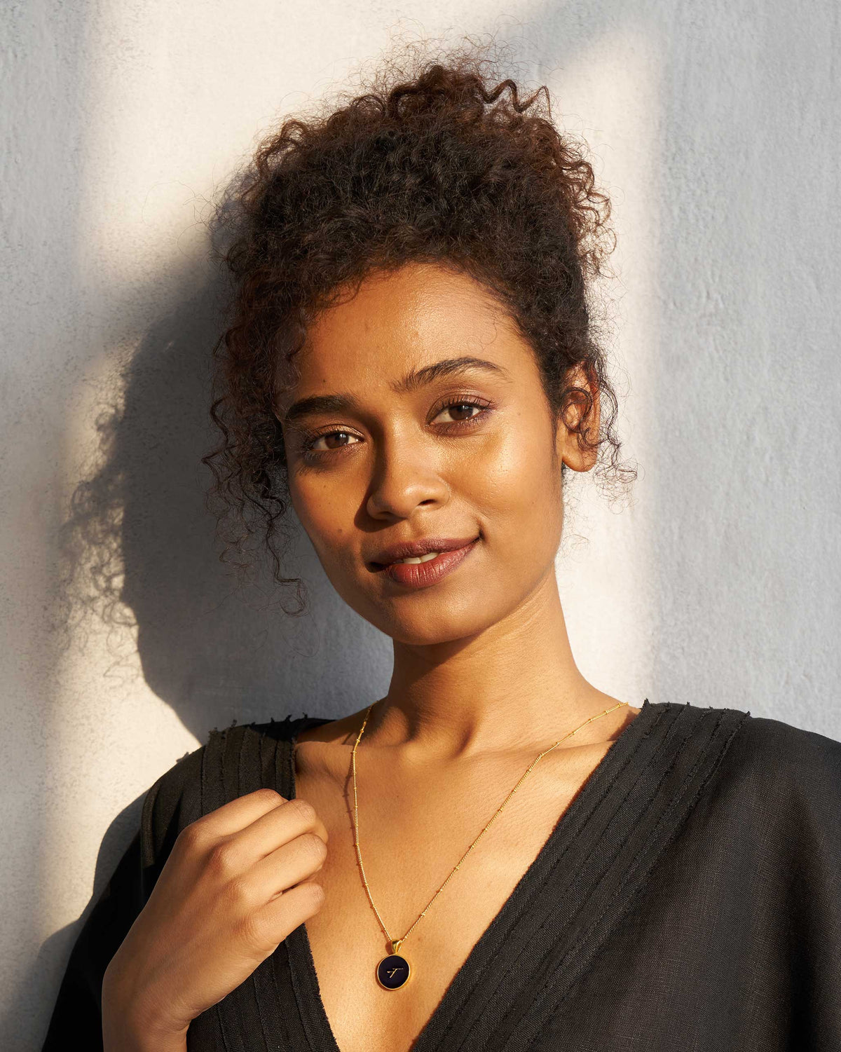 Person wearing a black and gold Alphabet N charm necklace.