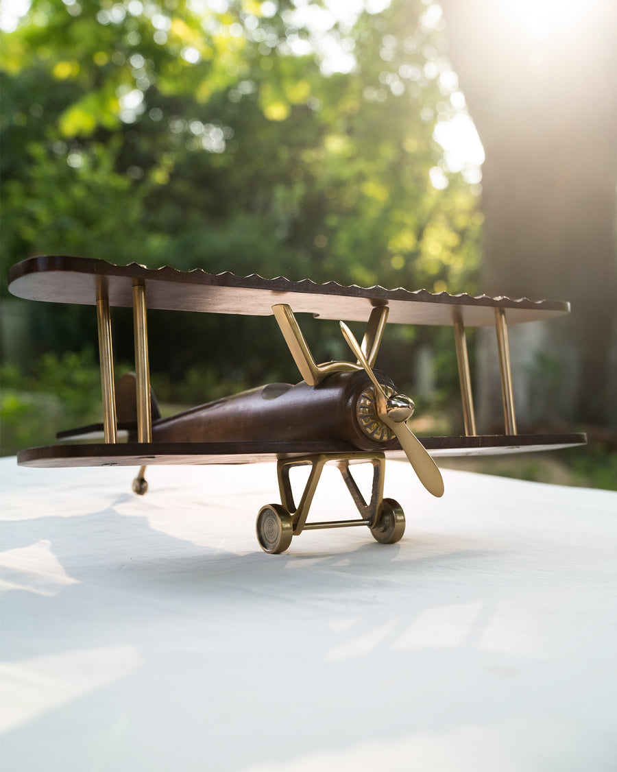Wood and brass Beufort biplane resting on a white surface.