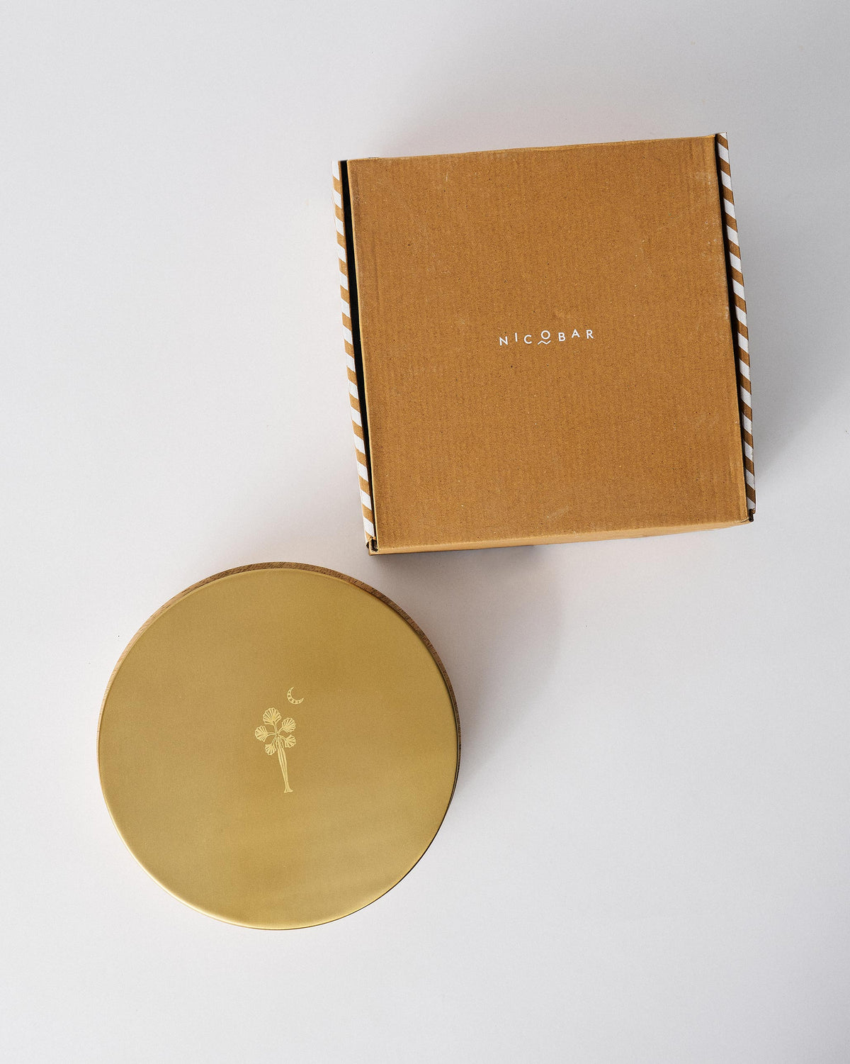 Chand spice box brass lid beside its brown Nicobar gift box.