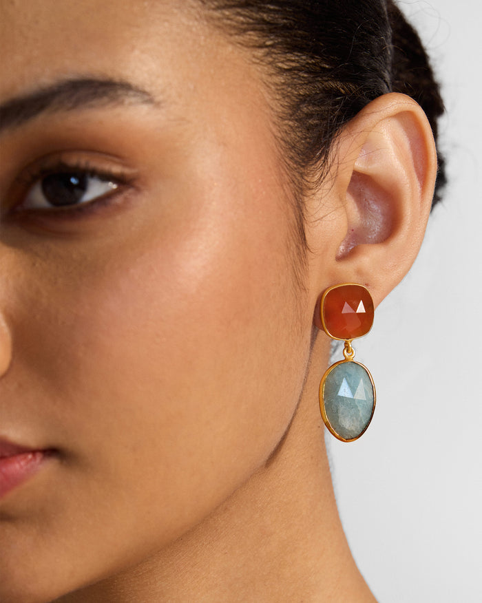 Side profile of orange and pale blue icy amber earrings on a person.