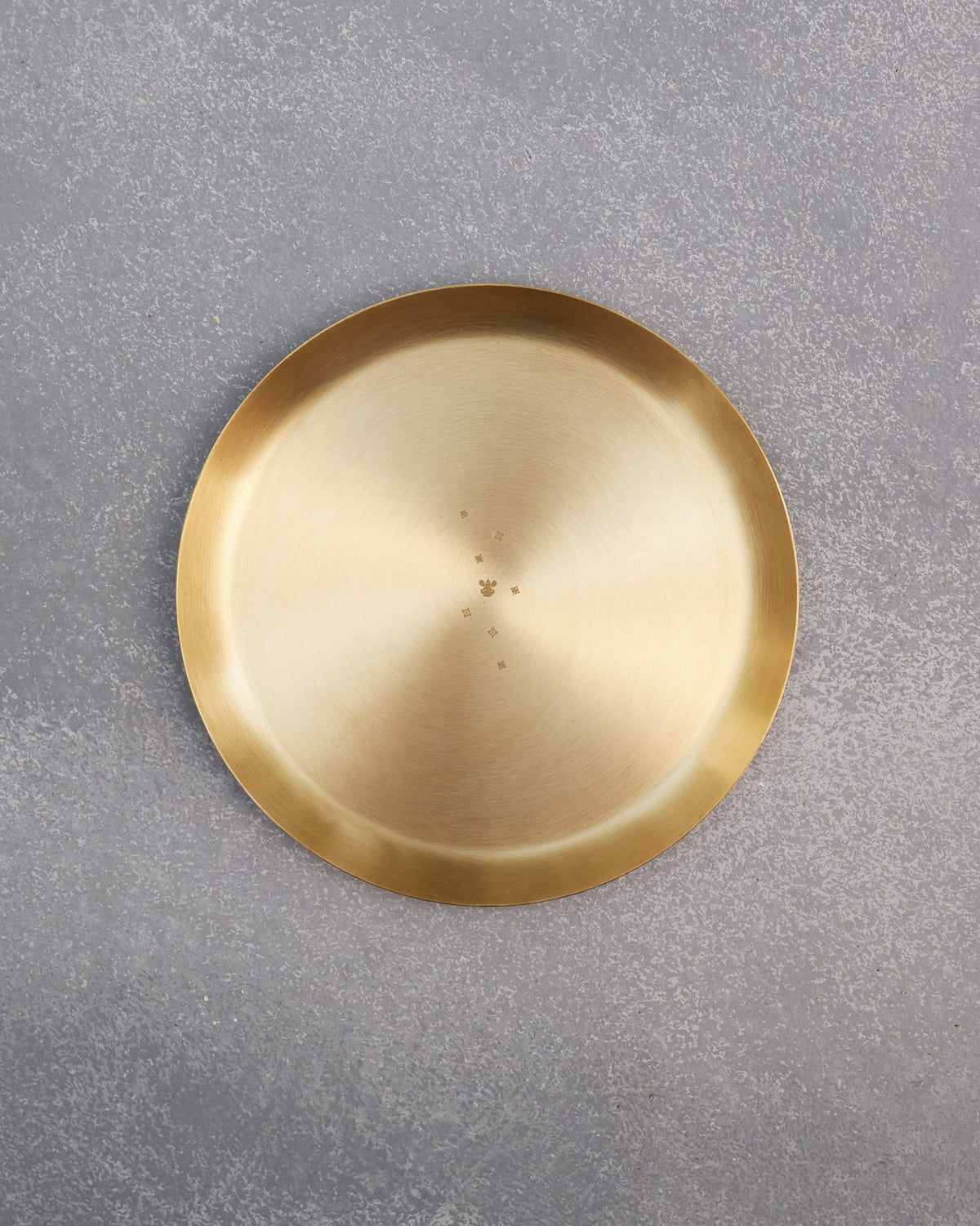 Overhead view of a round brass Madhu quarter plate.