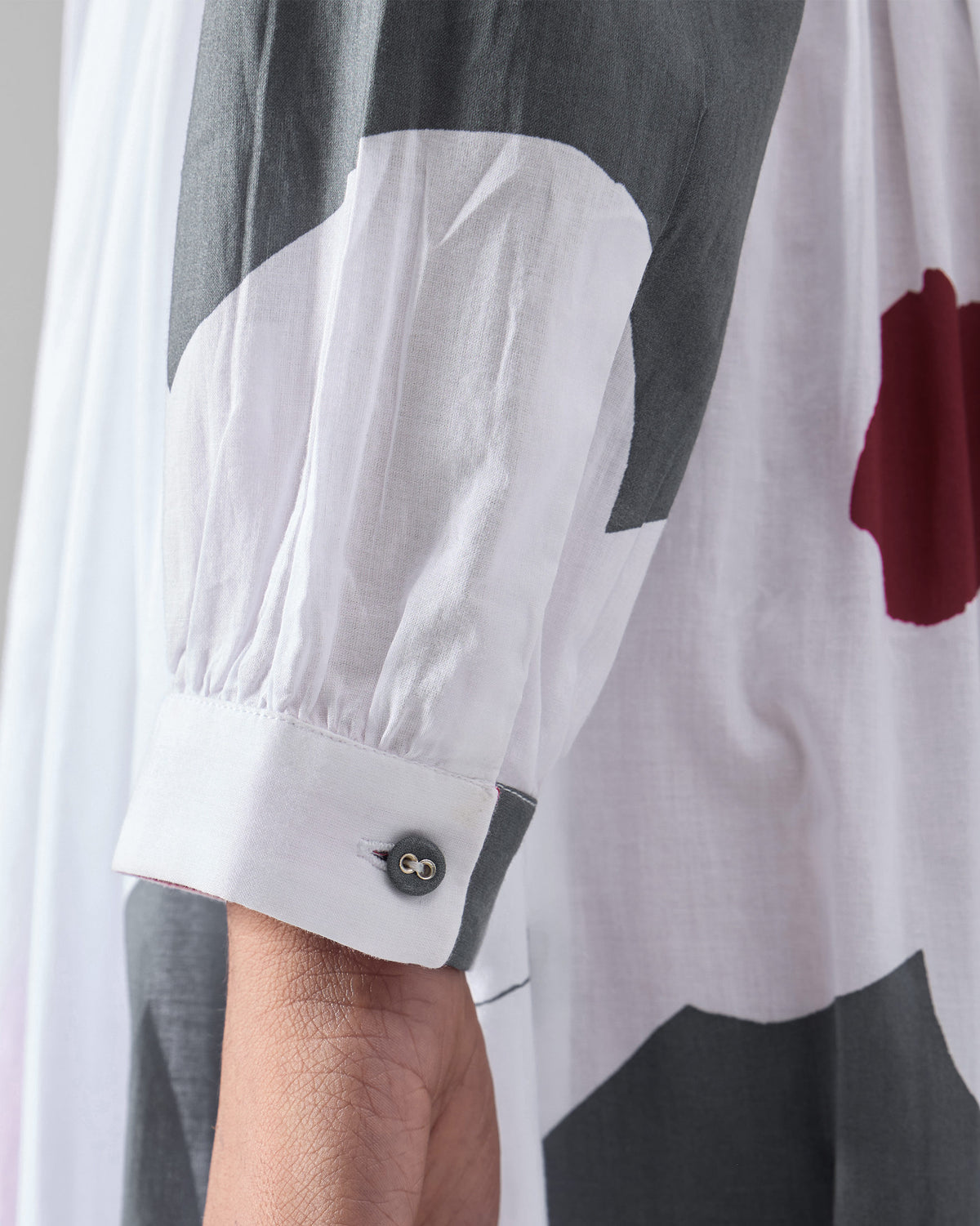 Close-up of the buttoned cuff on a white Nico wrap dress.