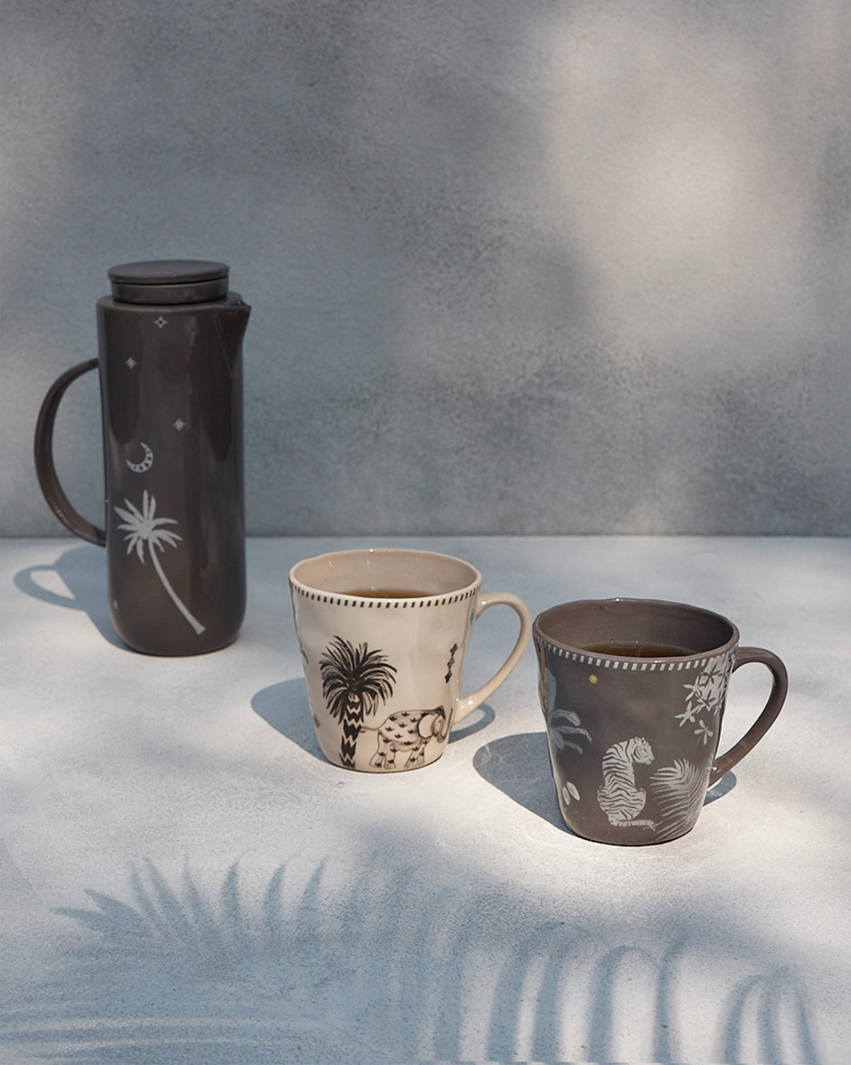 Cream and charcoal Malabar conical mugs with elephant and tiger motifs.