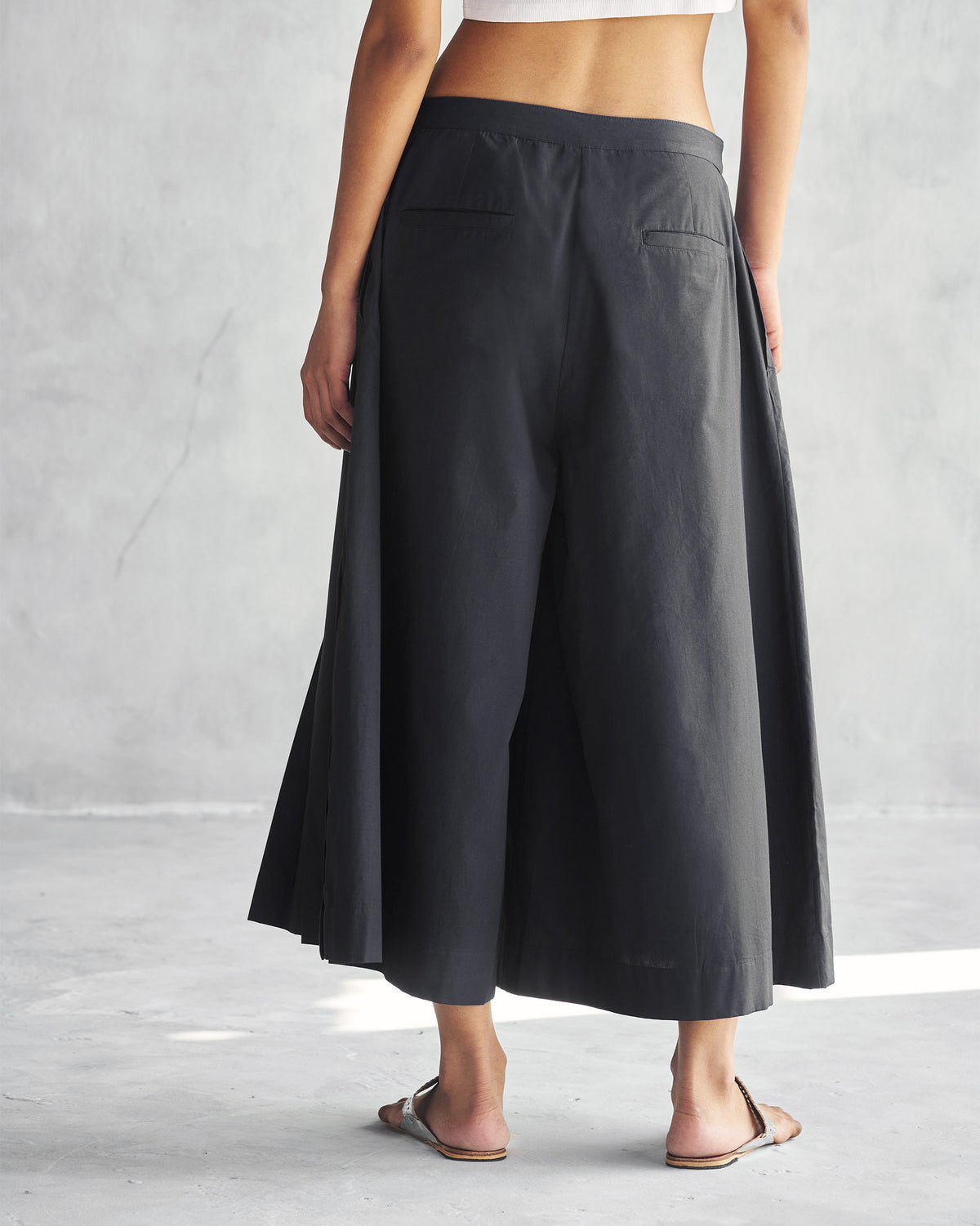 Back of black Pleated Flare Culottes with welt back pockets.