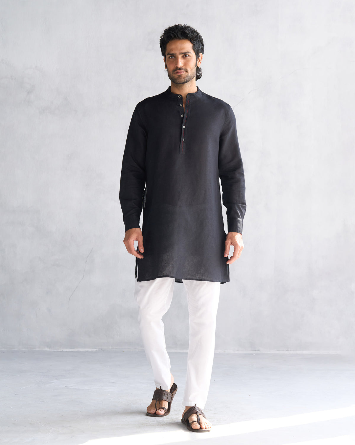Person wearing a black Chandni Chowk kurta with a button placket.