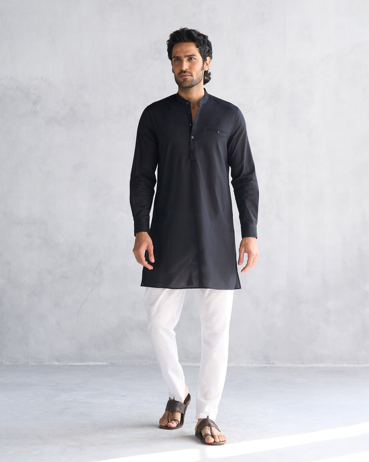 Full-length view of a black Pondicherry kurta worn with white trousers.