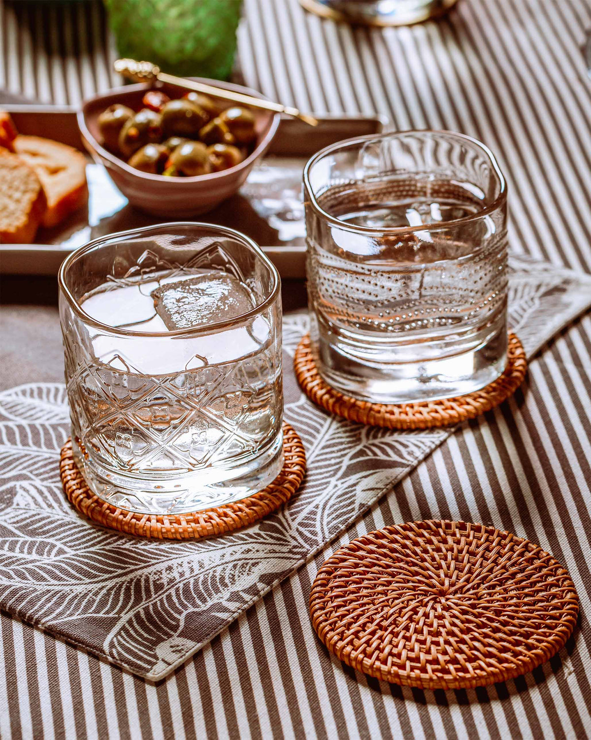 Mahi whiskey glasses with ice on woven coasters.