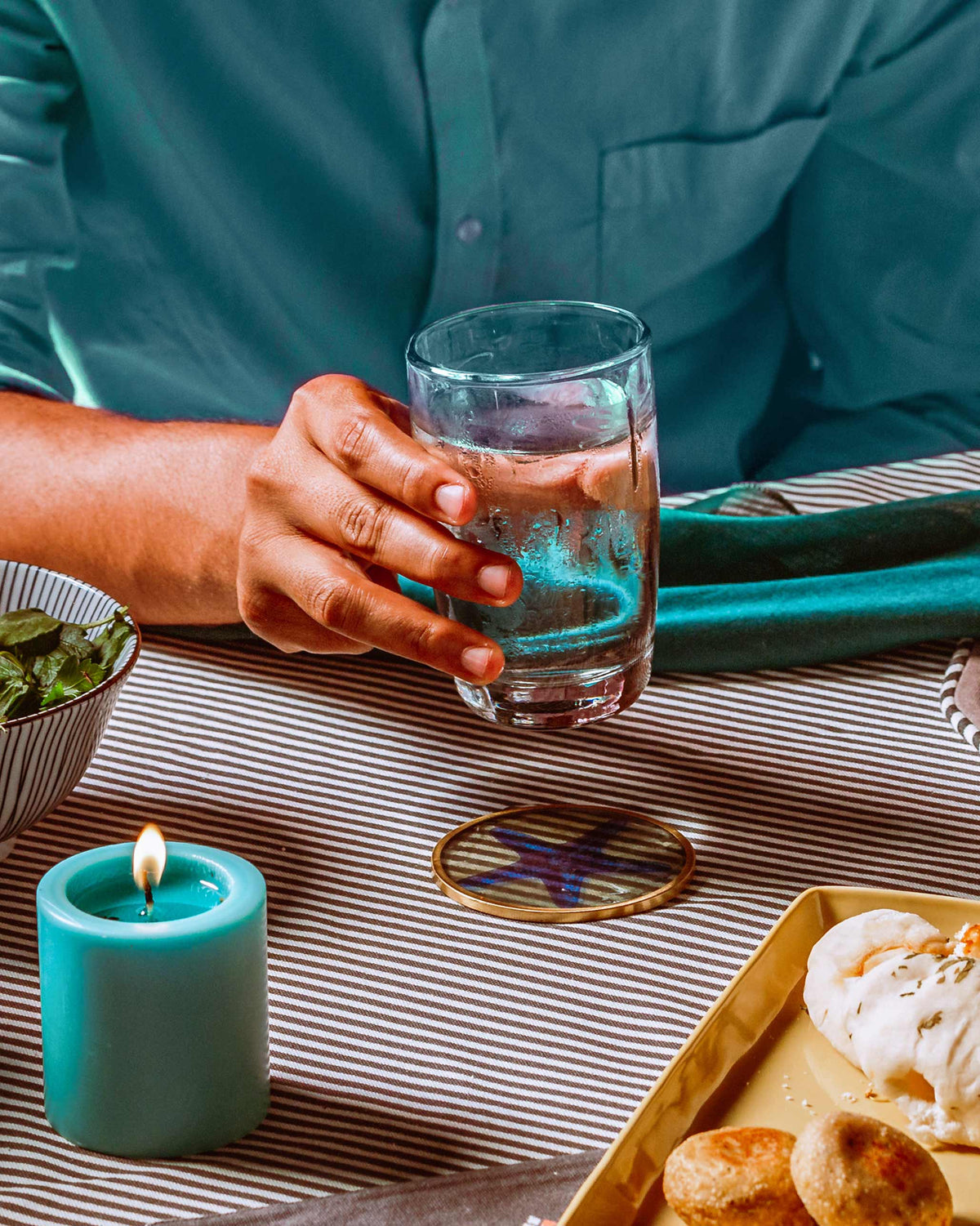 Person holding a clear Mahi long drink glass filled with water.