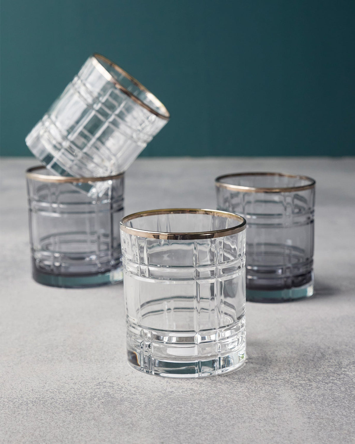 Clear and smoky Celeste whiskey glasses with a grid pattern and gold rims.