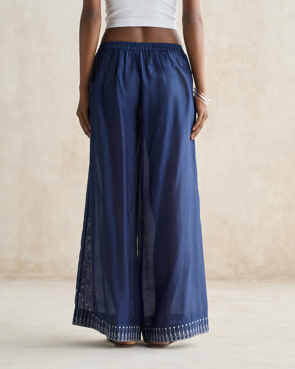 Back of navy sheer trousers with a white embroidered hem.