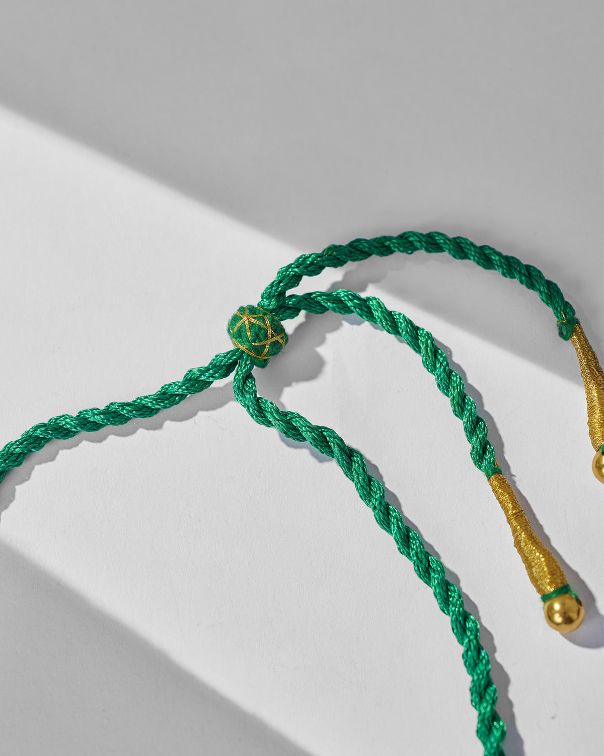 Close-up of the adjustable green cord on a gold zedi necklace.