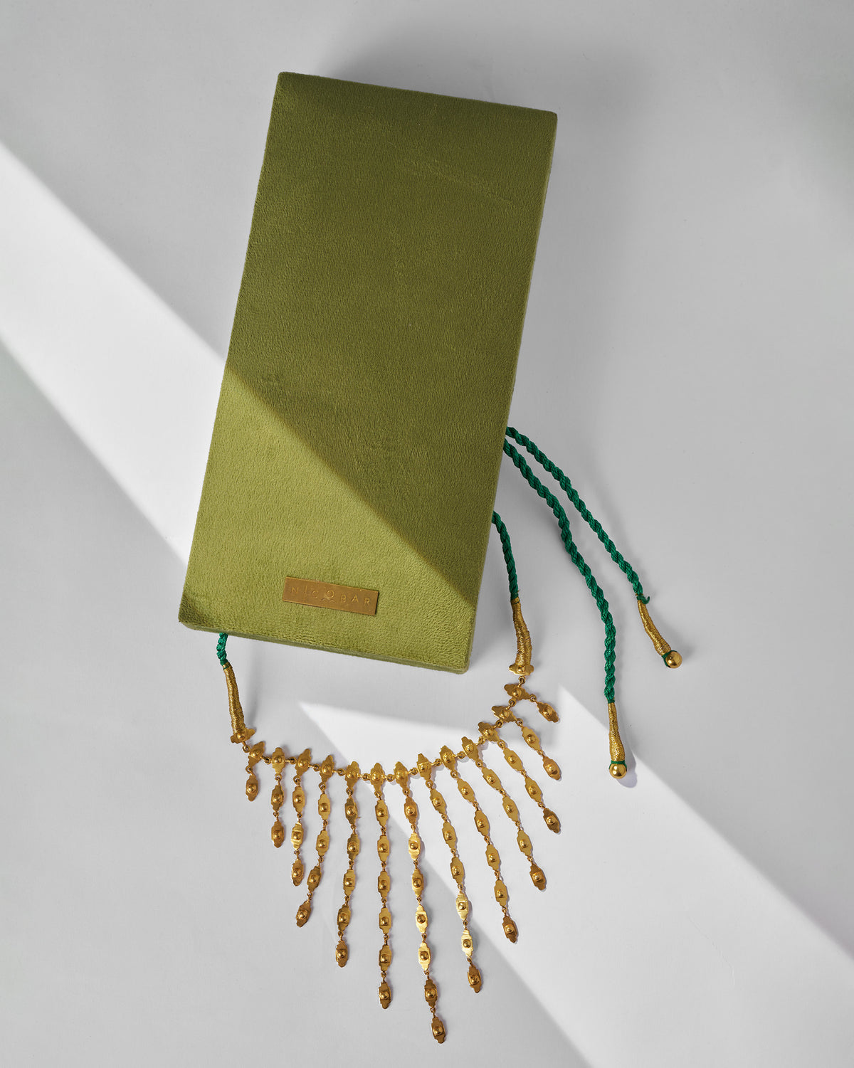 Gold zedi necklace beside a green Nicobar jewellery box.