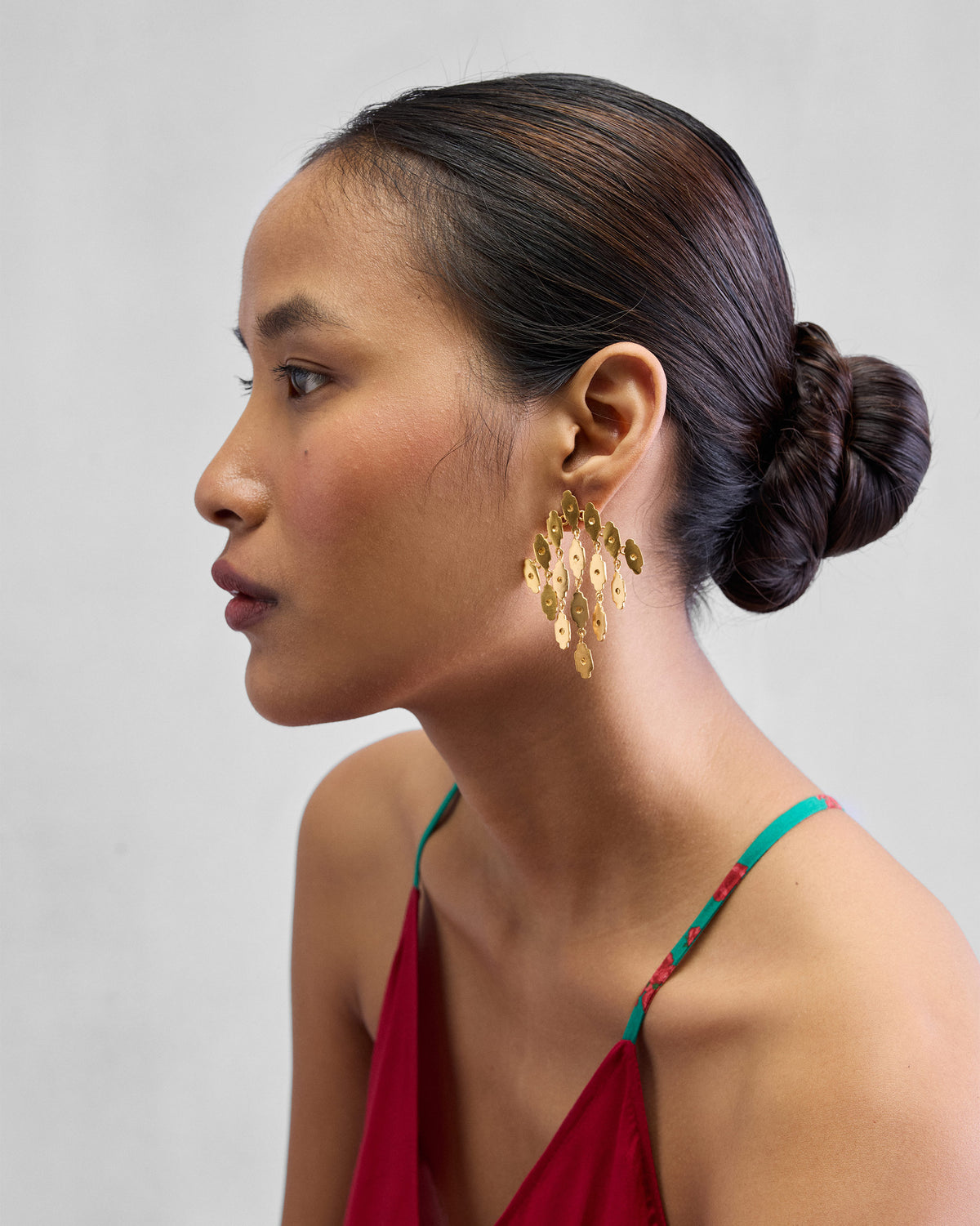 Side view of gold Zedi Drop Earrings worn by a person.