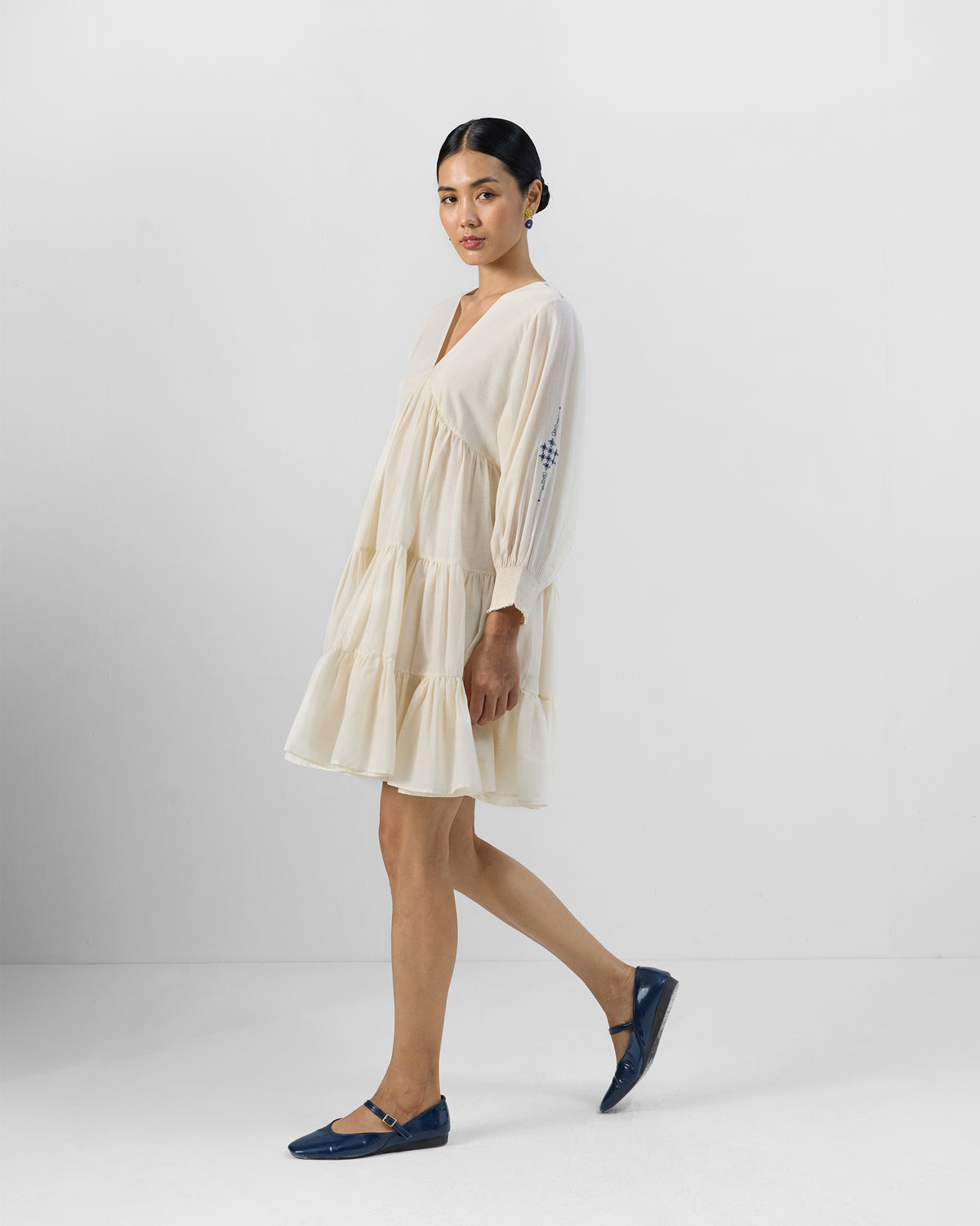 Side view of an ivory Temple tier dress with long sleeves.