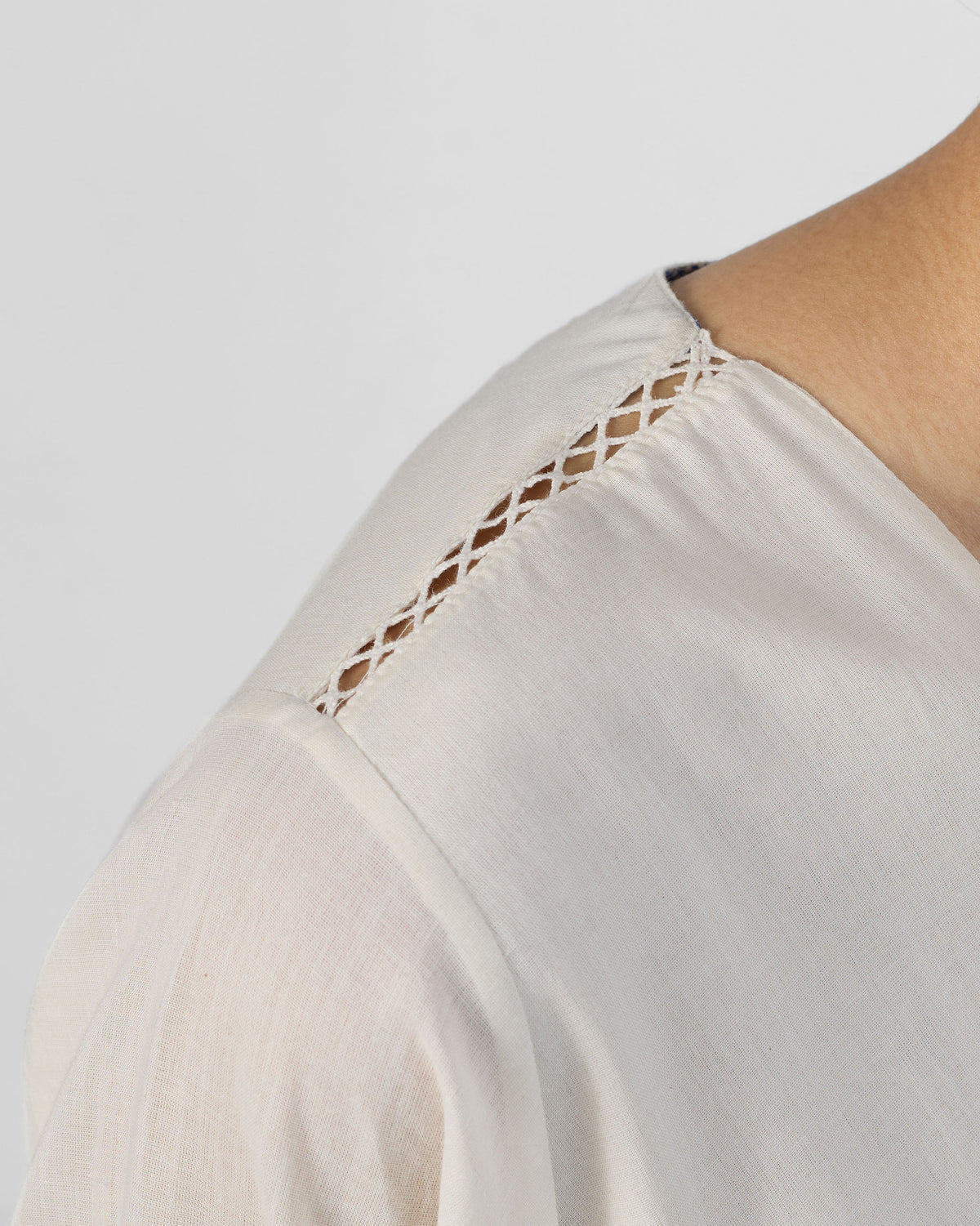 Close-up of a lattice shoulder seam on an ivory Temple tier dress.
